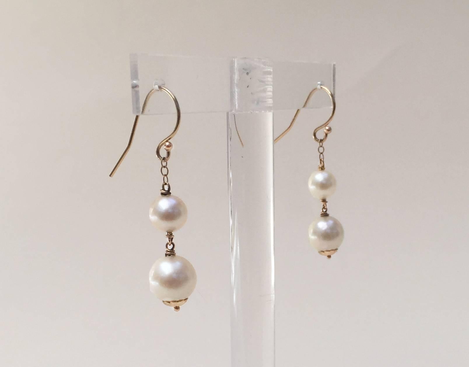 These simple, yet elegant double pearl earrings hang at approximately 1 inch. The small and large pearls play off of each other to shine more brilliantly. With 14k yellow gold hook and wiring the earrings have a golden warm hue. At the bottom of