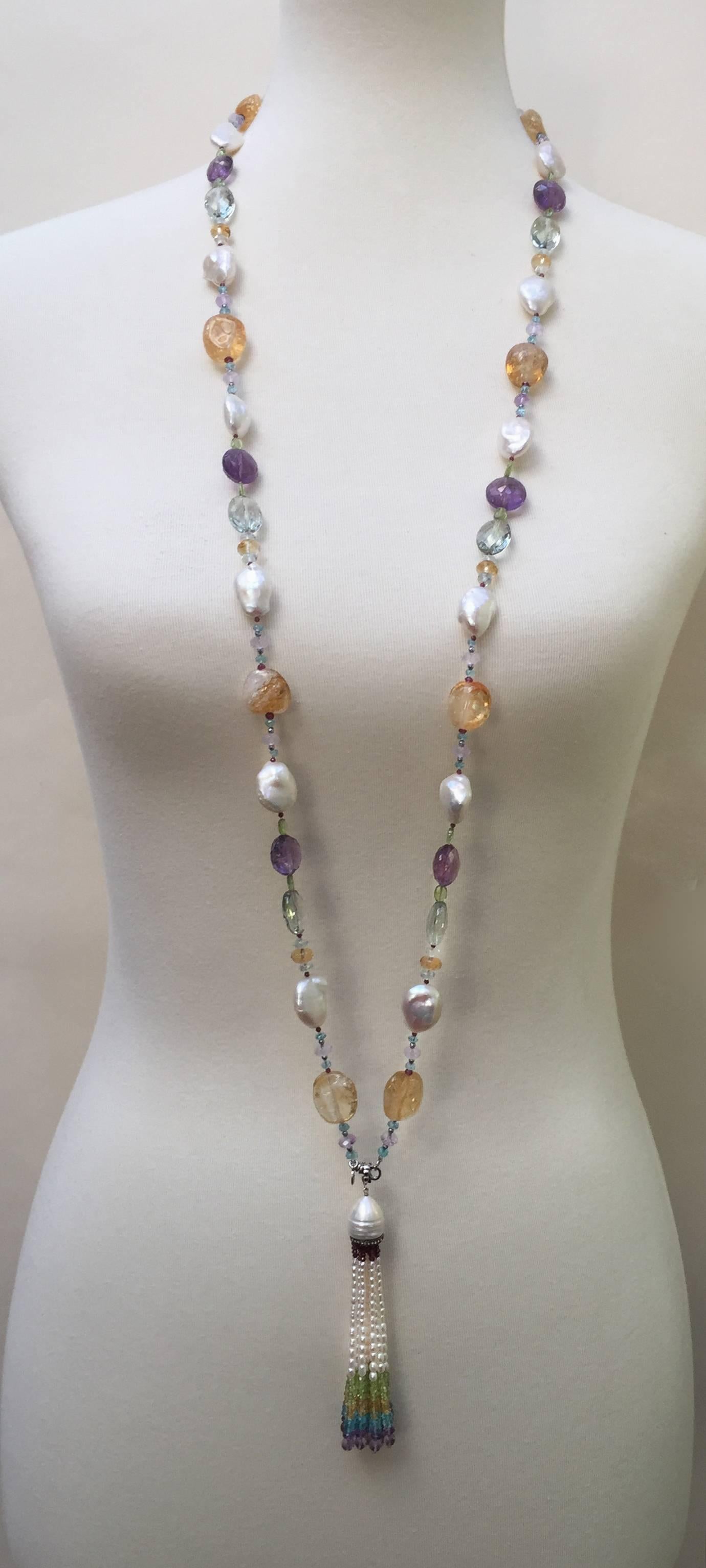 The pastel pallet of this sautoir is composed of large citrine, pearl, peridot, and aquamarine smooth and faceted stones. Playing off of those colors are smaller rose quartz, garnet, blue topaz, and peridot beads. The darker tone of the large