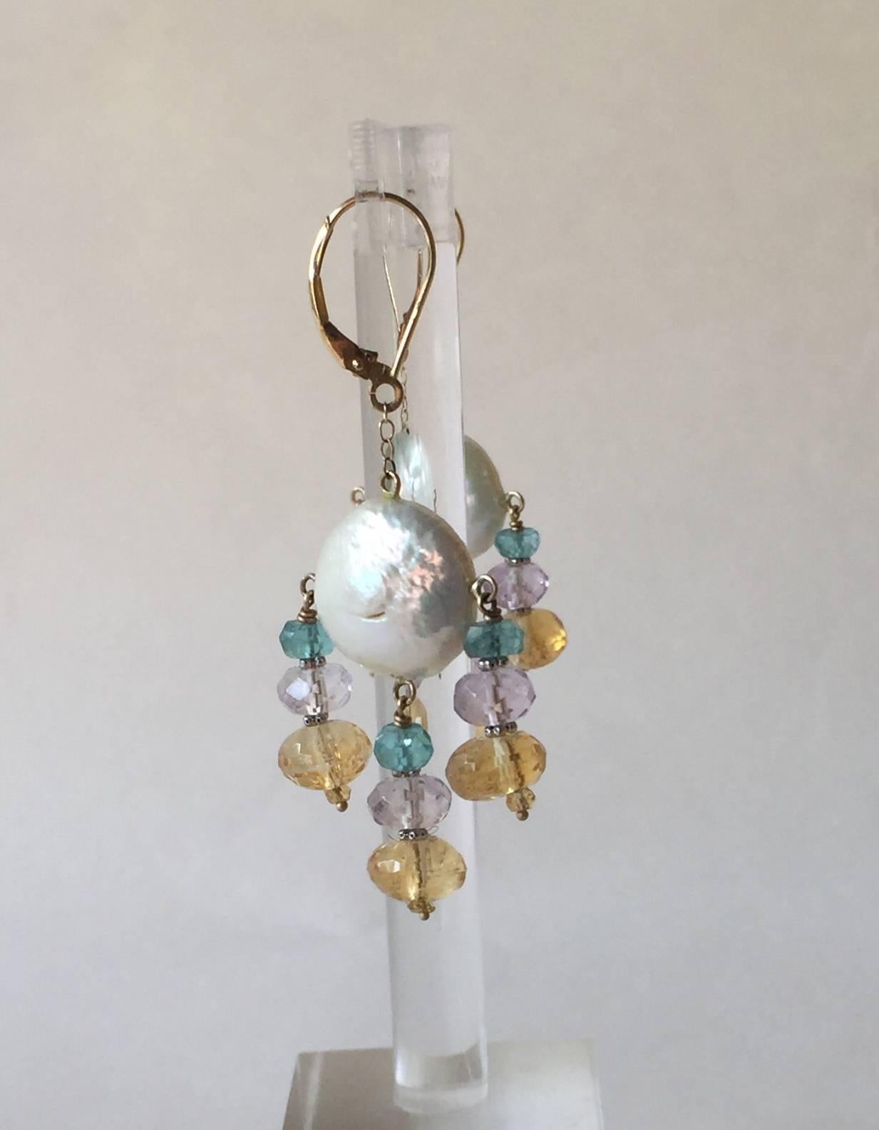 These fun and whimsical earrings are composed of graduated and faceted blue topaz, amethyst. and citrine. Highlighting the shine of the stones are small 14k white gold beads. Completing these elegant and light earrings are coin pearls and 14k yellow