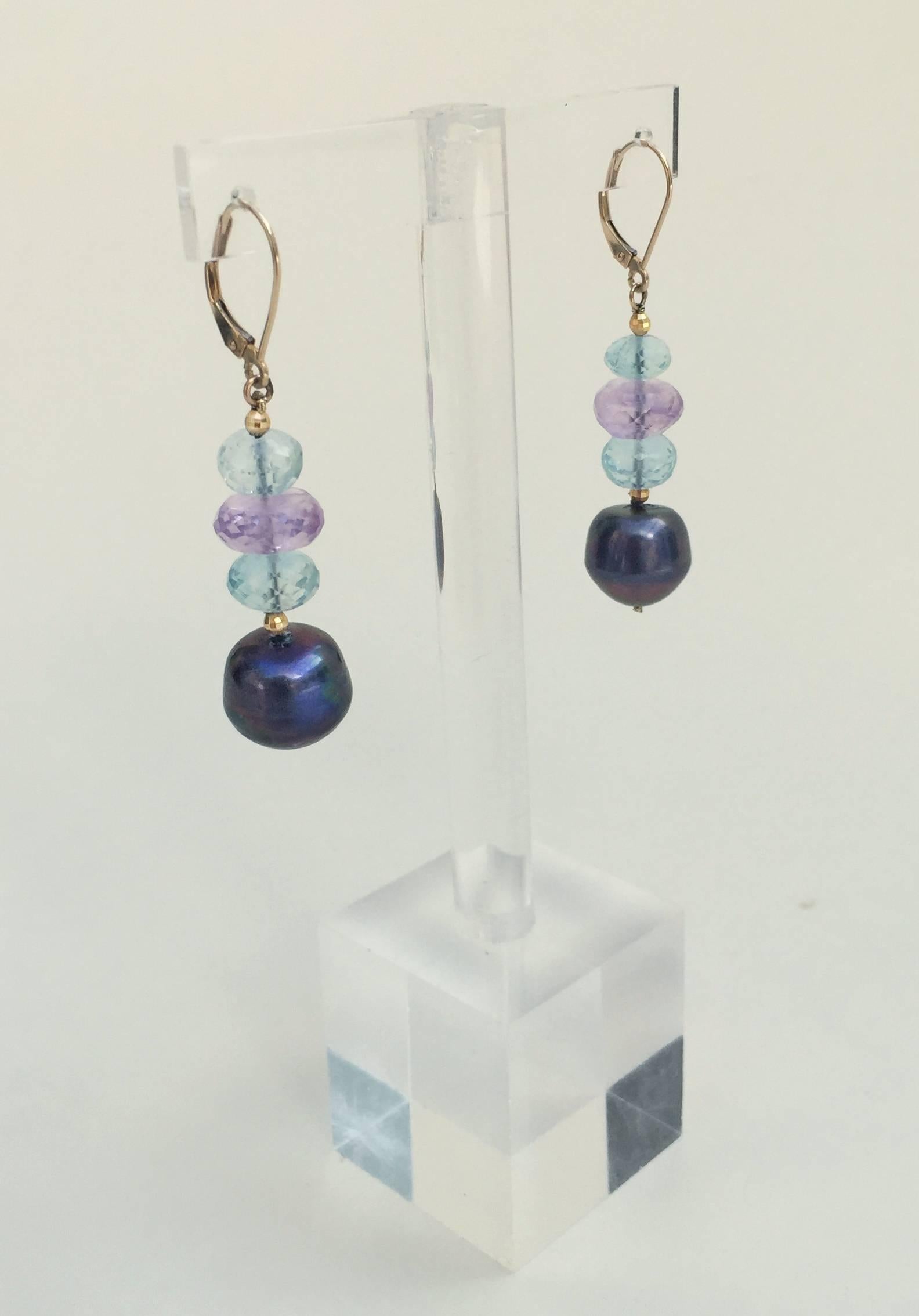 These 1.75 inch long earrings are composed of blue topaz, amethyst, and baroque black pearl beads. The earrings are secured with a 14k yellow gold lever back and hang perfectly to frame the face. 

*These earrings are a great match with any original
