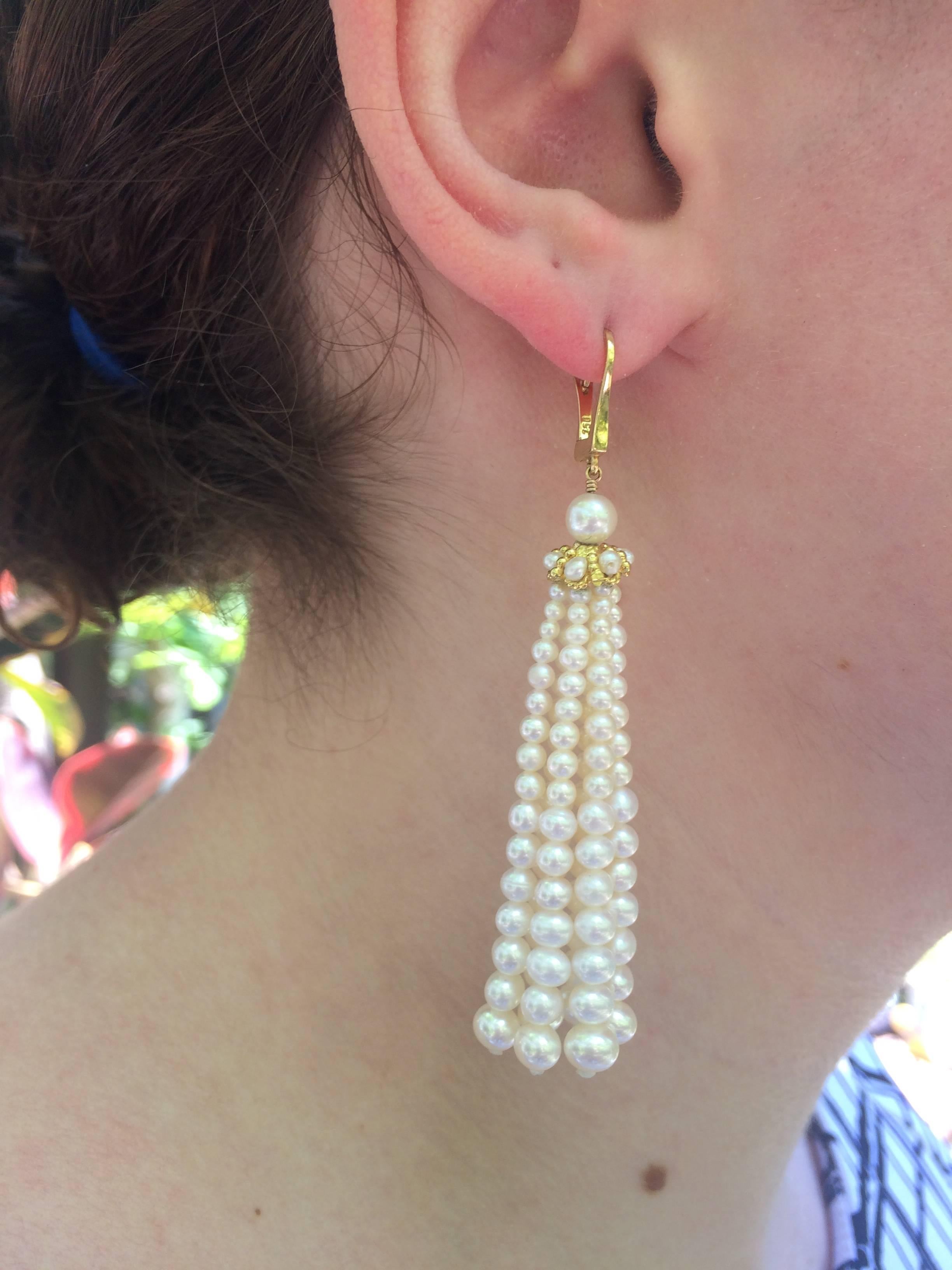 Graduated fine cultured pearl earrings measures 3 inches from top of ear wire. Pearl strands hang from yellow gold cups detailed with pearls. 14 k yellow gold ear wires.