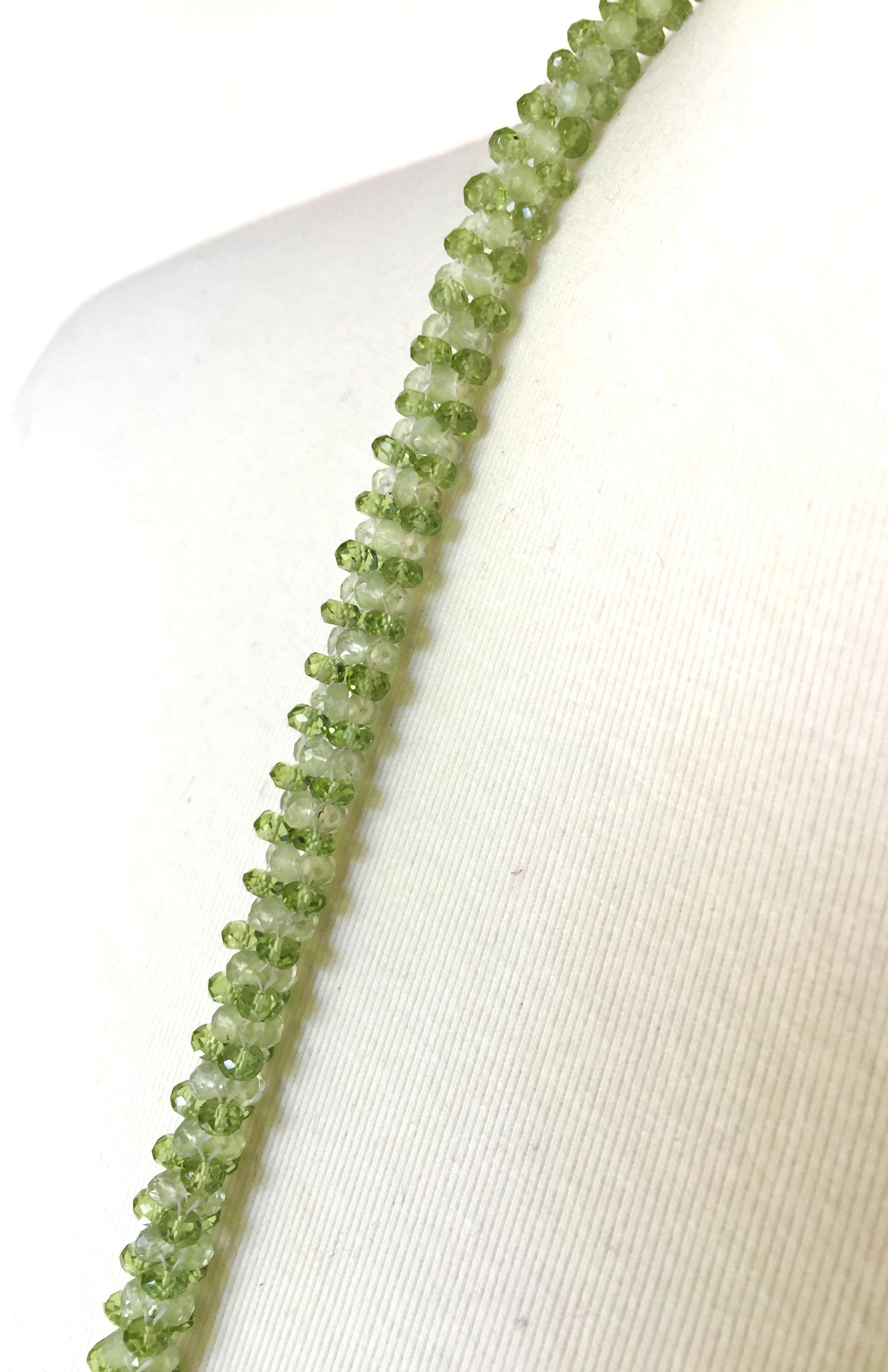 This art deco inspired peridot tassel rope necklace, with 14 k yellow gold, gold plated cup, and diamonds, is composed of glittering faceted green peridot beads of two tones. The ropes necklace is finished with an elegant 5