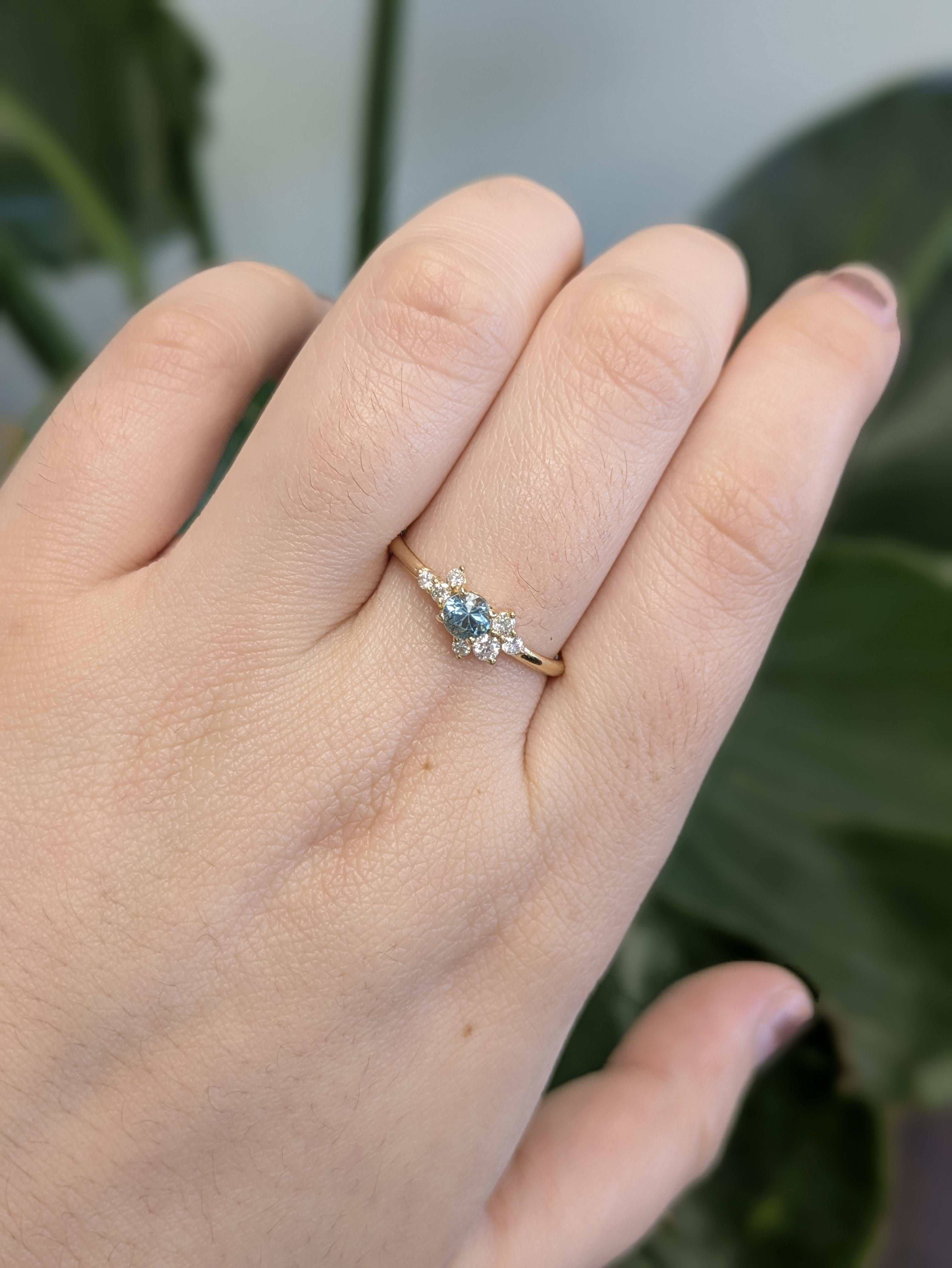 Questo delicato anello mette in mostra uno zircone blu cambogiano rotondo da 0,32 carati, compensato da scintillanti accenti di diamanti color terra in un elegante design asimmetrico. Realizzato in oro giallo massiccio 14 carati, è il tocco di