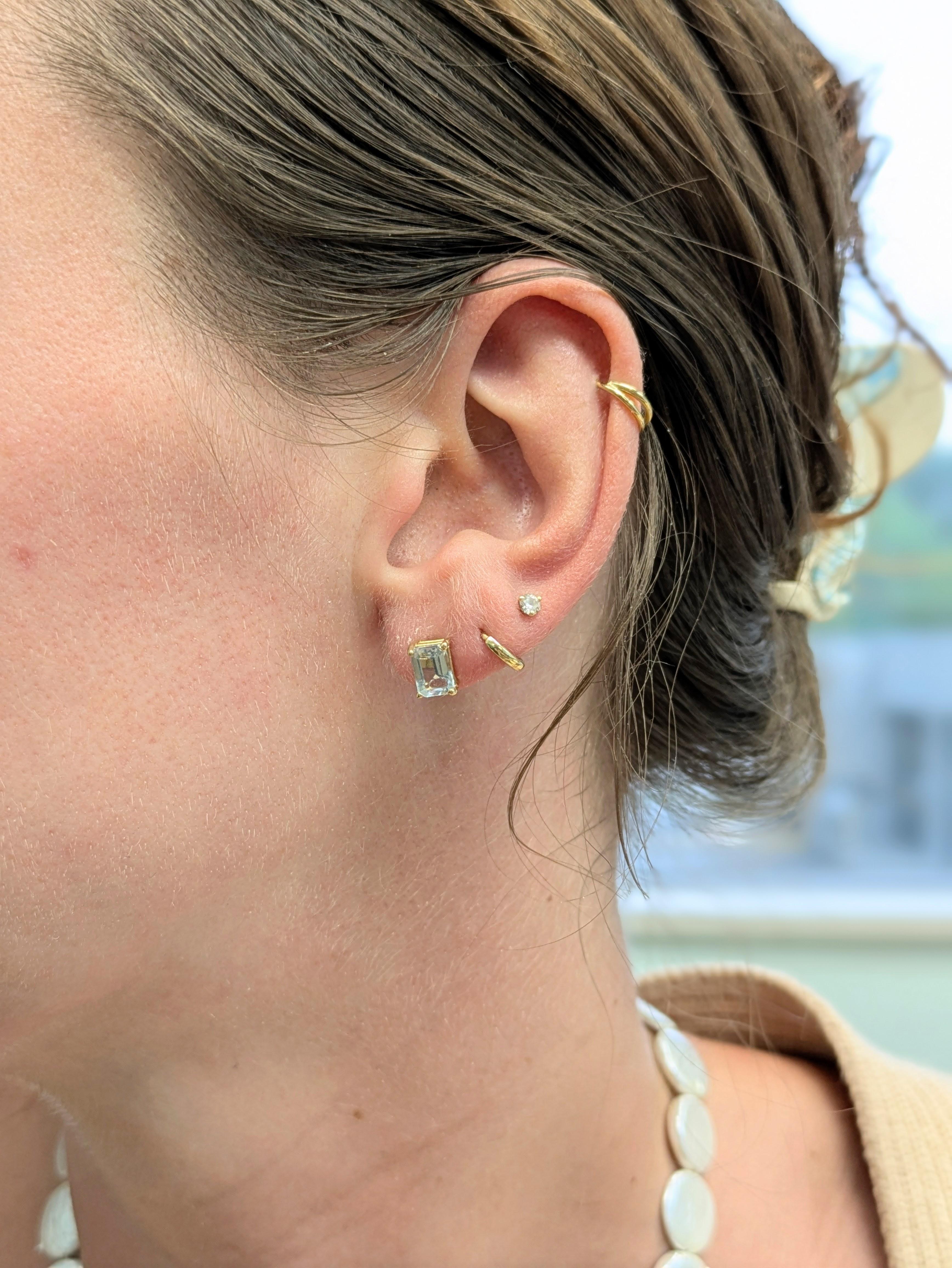 Eleganti e sofisticate, queste borchie solitarie presentano un'acquamarina brasiliana con un elegante taglio a smeraldo. Incastonati in oro massiccio 14k con un design minimalista a 4 punte, sono il lusso ideale per tutti i giorni: semplici, senza