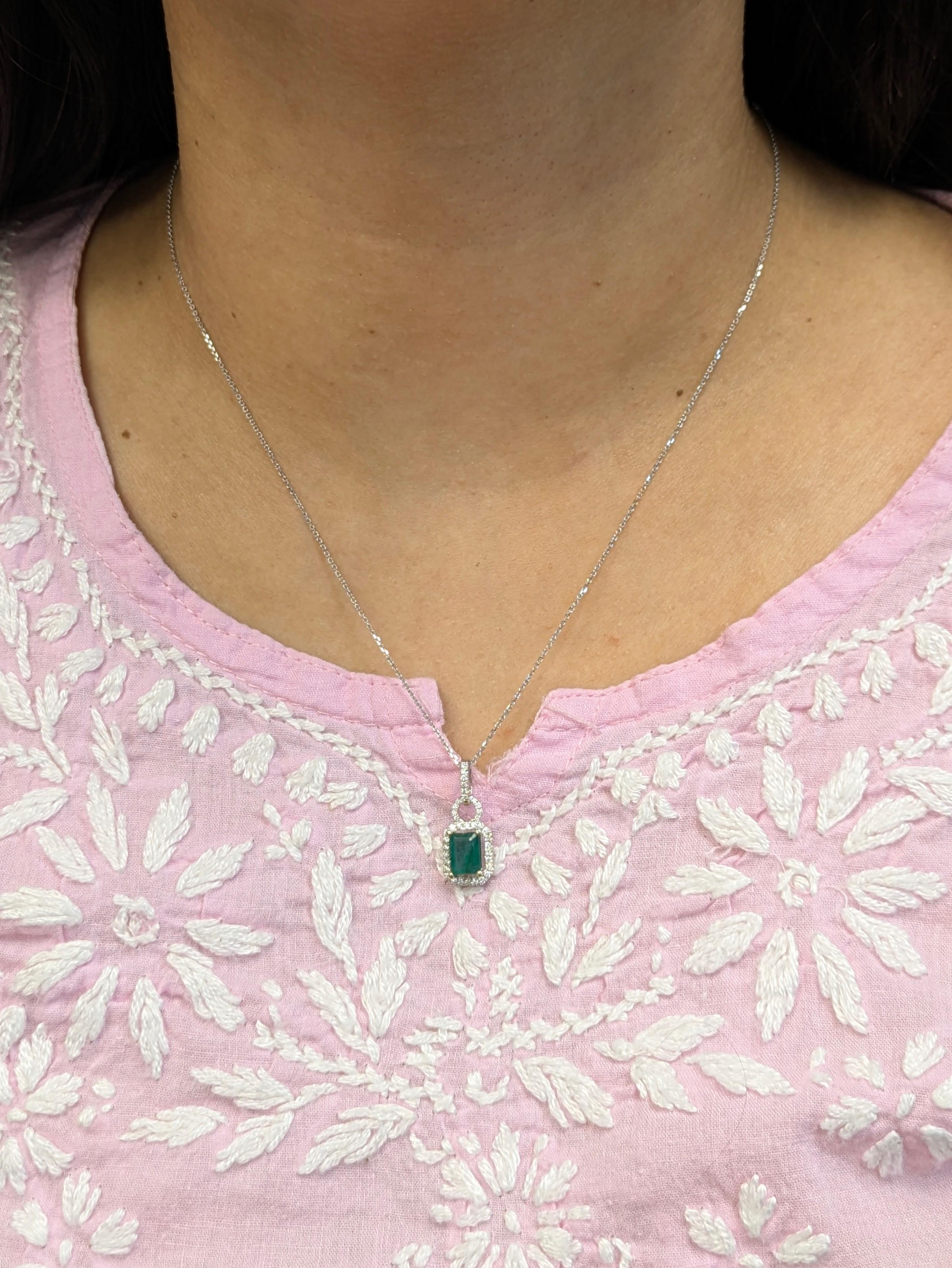 Dieser zarte und raffinierte Anhänger besteht aus einem natürlichen sambischen Smaragd von 1,22 Karat, der von einem funkelnden Diamantenhalo umgeben ist und mit einem Pavé-Diamantenbügel akzentuiert wird. Der aus massivem 14-karätigem Weißgold