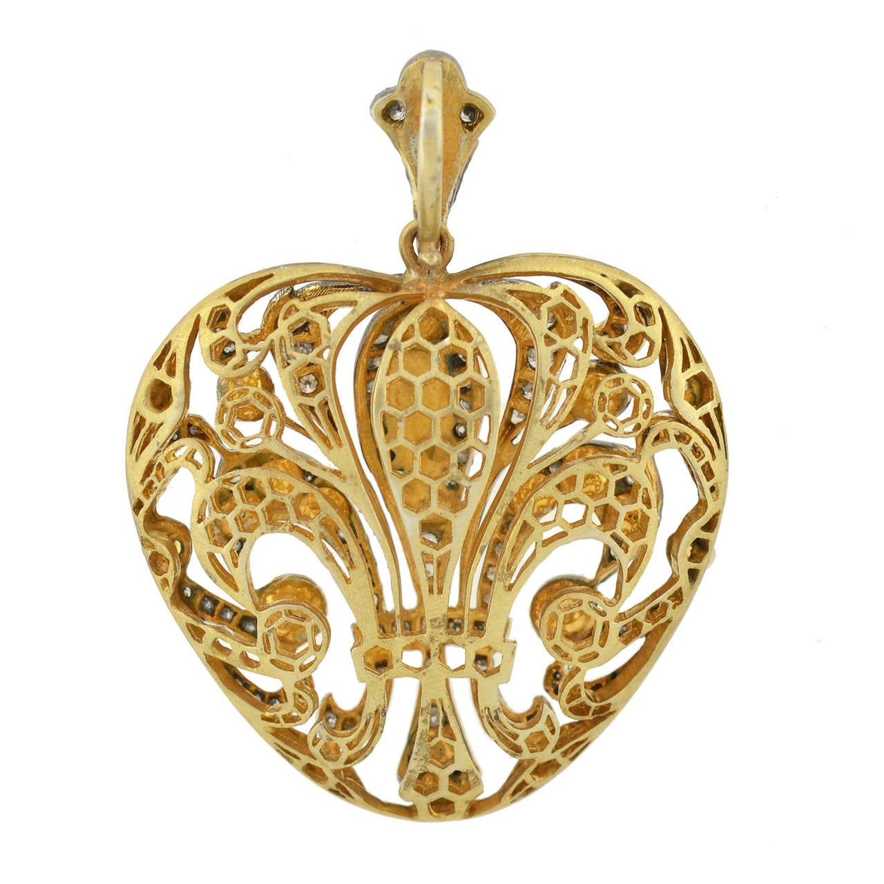 A spectacular fleur-de-lys heart pendant from the Edwardian era! This gorgeous three-dimensional heart pendant has a lacy filigree design that forms a beautiful fleur-de-lys on both sides. Decorating the entire front surface of the piece are