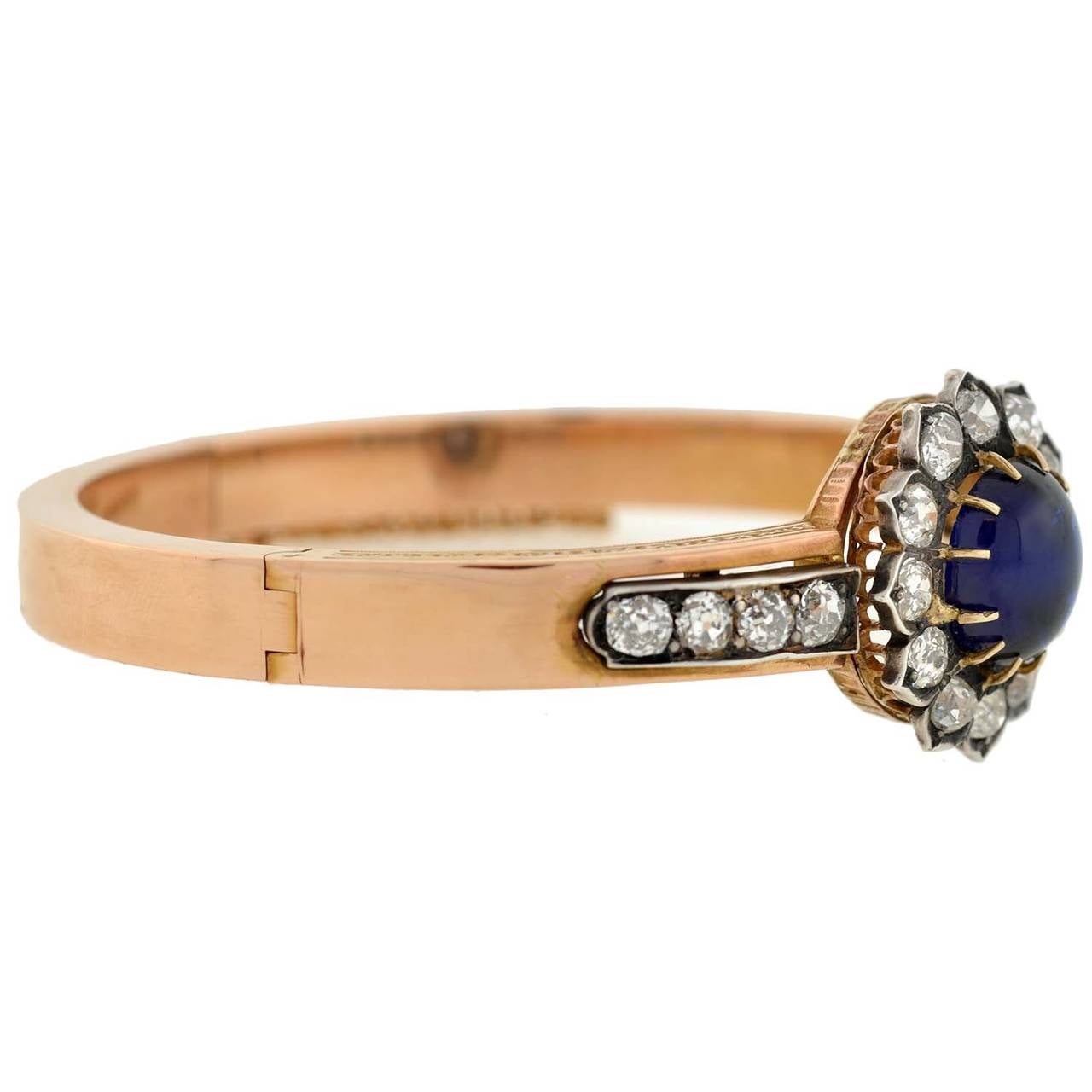 A spectacular sapphire and diamond bracelet from the Victorian era (ca1880)! Made of vibrant 18kt yellow gold, the bracelet is a hinged bangle style with a stunning gemstone-encrusted face. Resting at the center is a magnificent cabochon sapphire