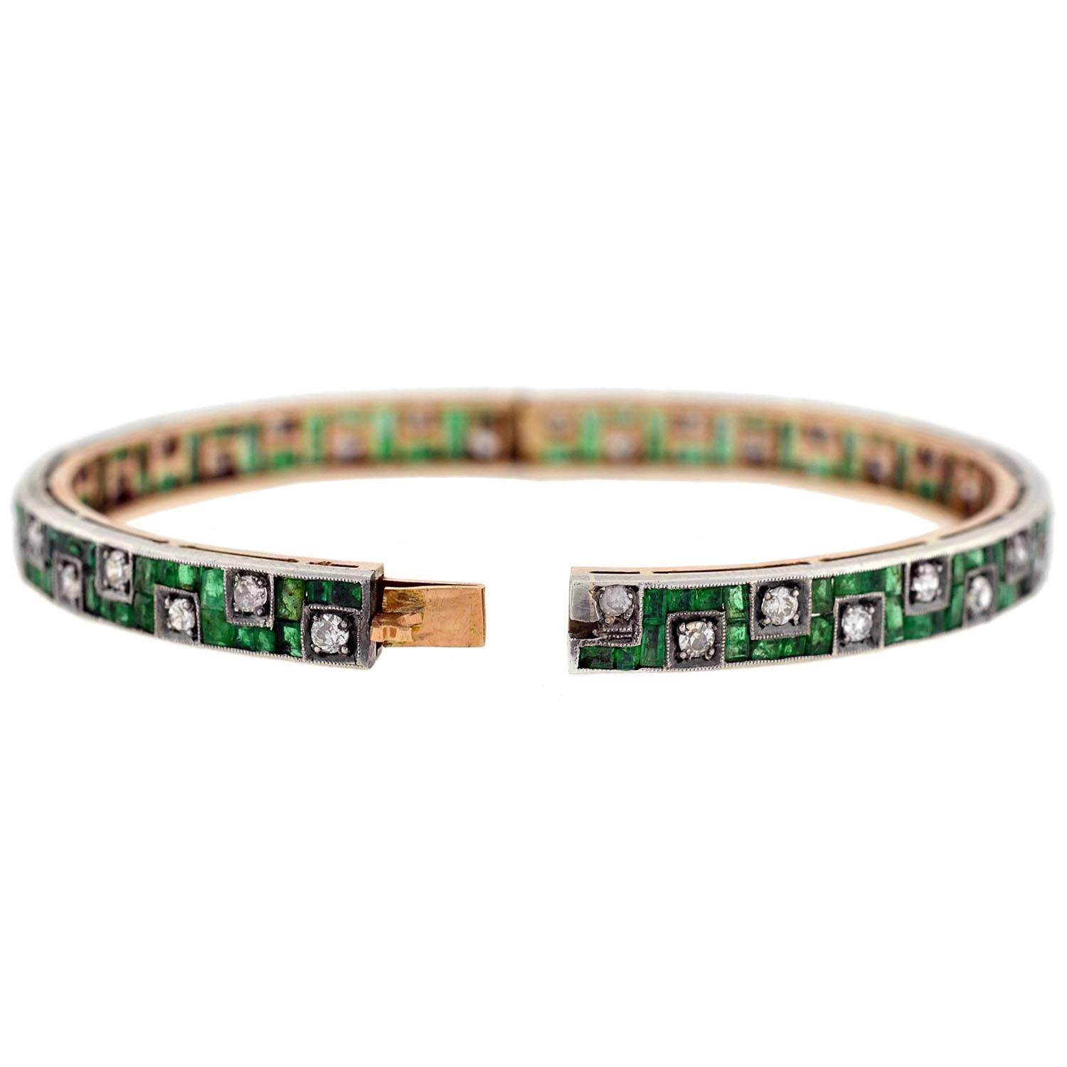A rare and unusual bracelet from the Late Edwardian (ca1910) to Early Art Deco (ca1920) era! This magnificent bangle has a mixed metals fabrication made of platinum-topped 14kt gold, and displays a spectacular emerald and diamond design. The