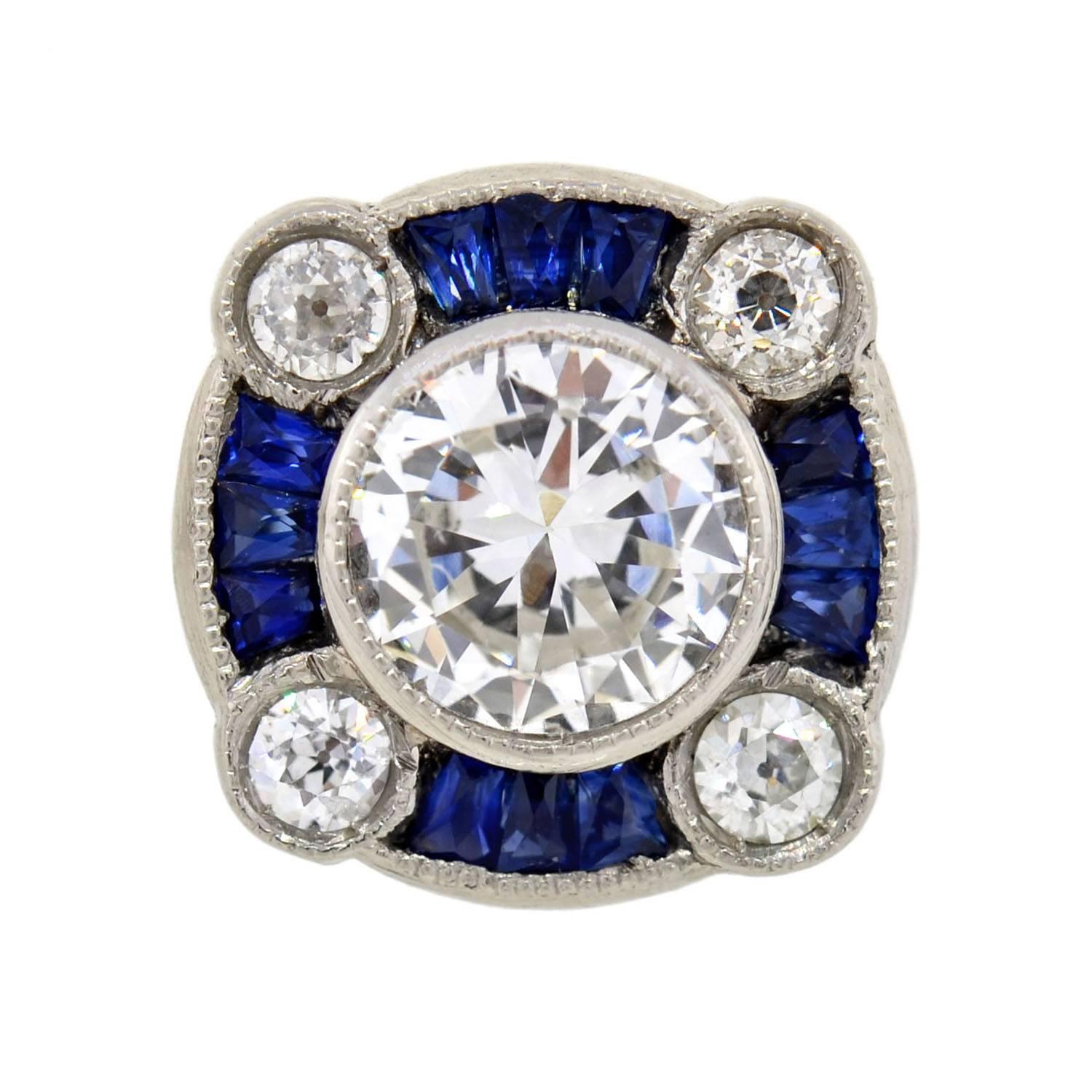 A stunning pair of diamond and sapphire studs inspired by the Art Deco era! Each platinum earring holds a sparkling Brilliant Cut center diamond set within a milgrained bezel setting. The central diamonds have an approximate total weight of 1.20ct