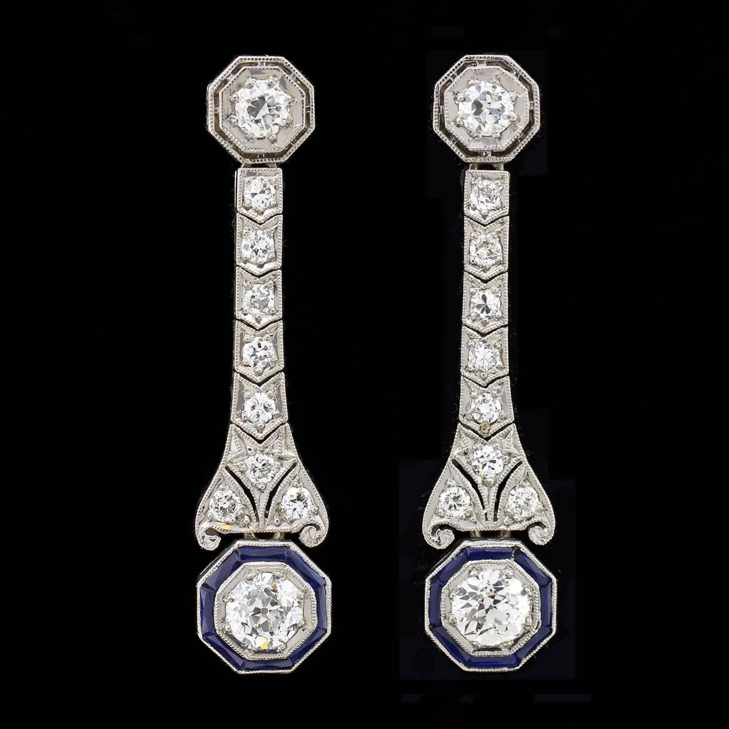 Absolutely exquisite diamond and sapphire earrings from the Art Deco (ca1920) era! Each gorgeous earring is made of platinum and begins with a single diamond surmount. The diamond is set within an octagonal-shaped mounting that displays cutouts and