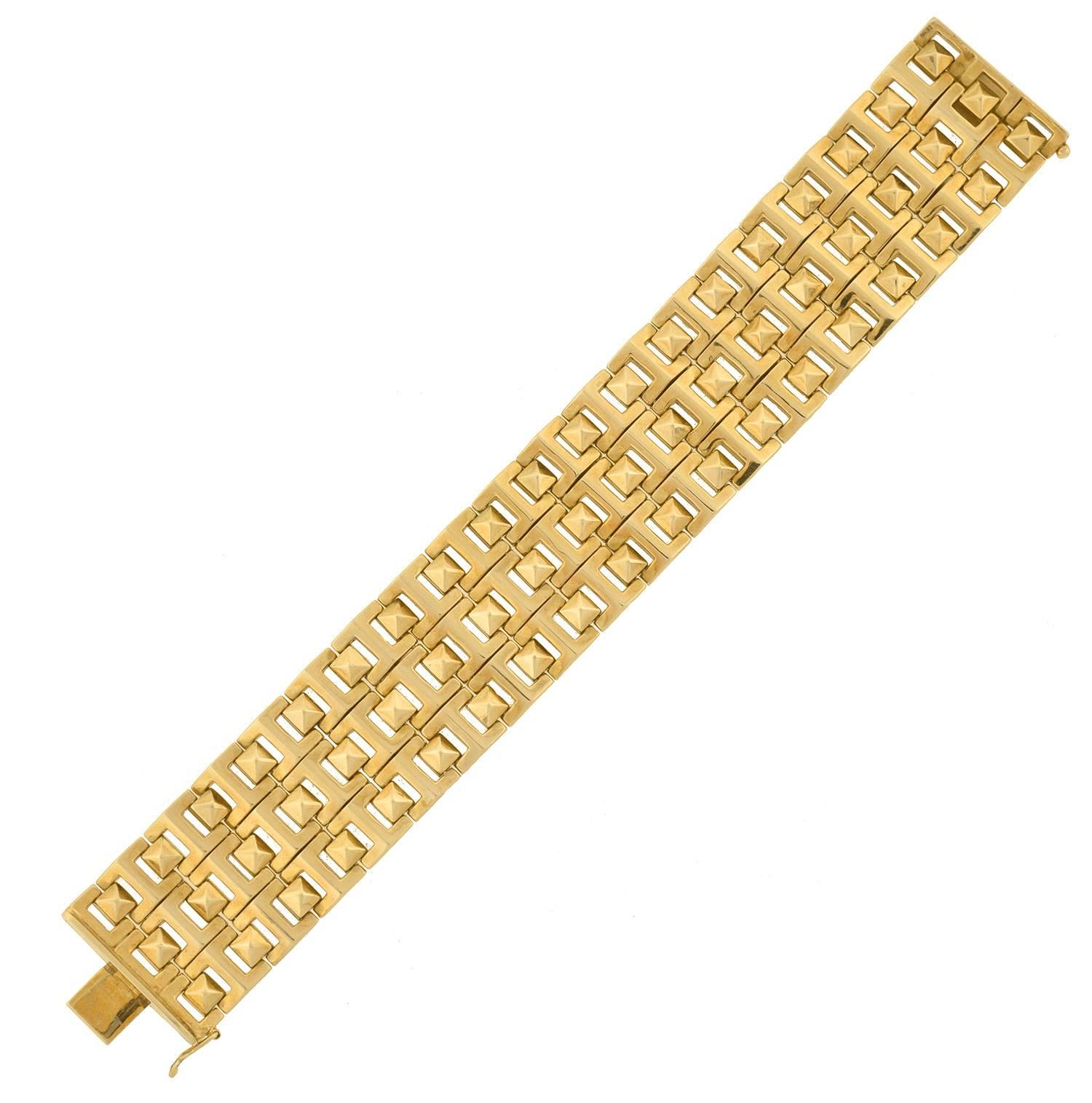 This fabulous estate bracelet makes a very stylish, modern statement piece! Crafted in 14kt yellow gold, it has a substantial appearance formed by rows of hinged links. A pattern of pyramid-shaped studs rest in between open squares, giving a