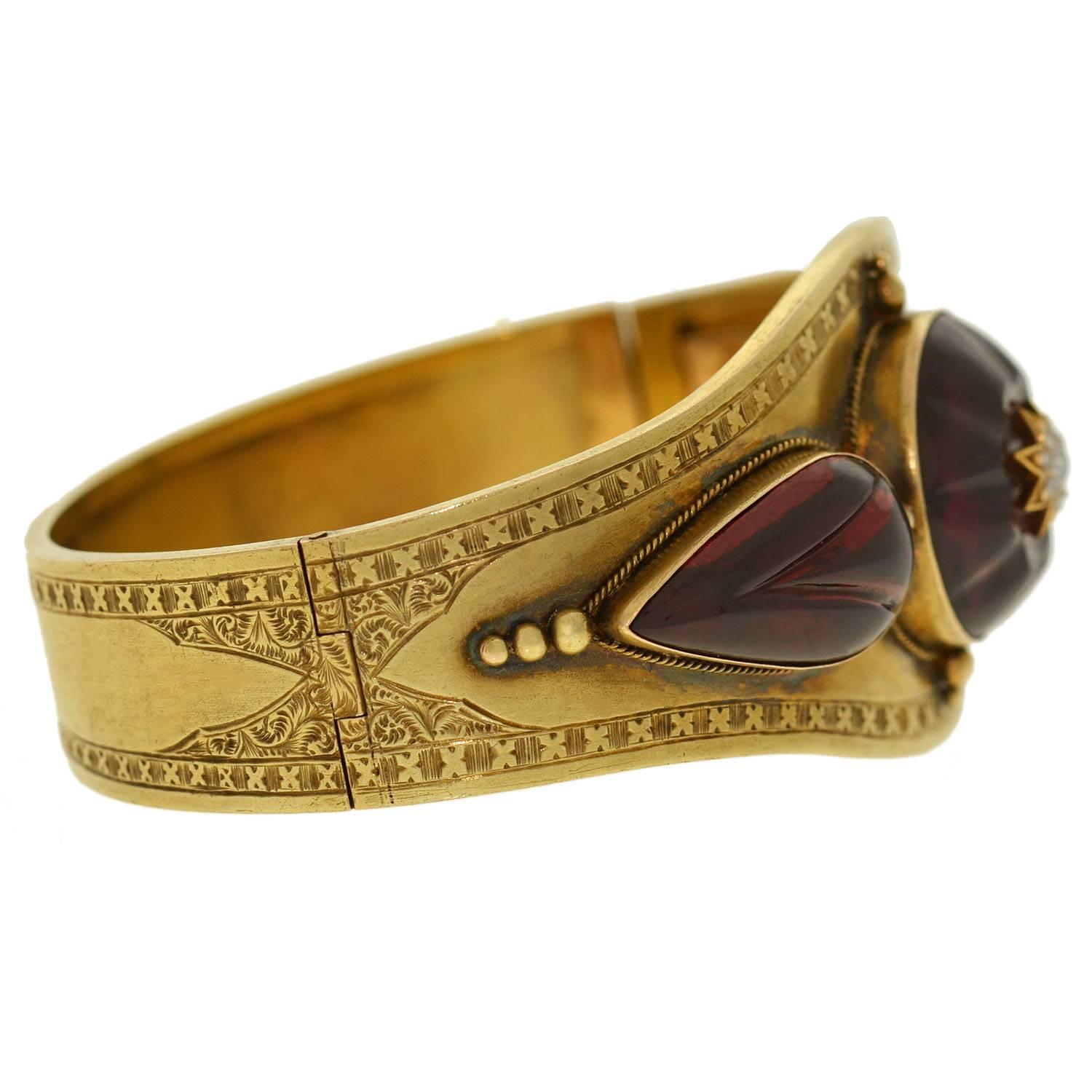 An absolutely exquisite garnet and diamond bangle bracelet from the Victorian (ca1880) era! This wide bangle is made of vibrant 15kt yellow gold and has a fantastic 3-dimensional design on the front surface. At the center of the bracelet is a round