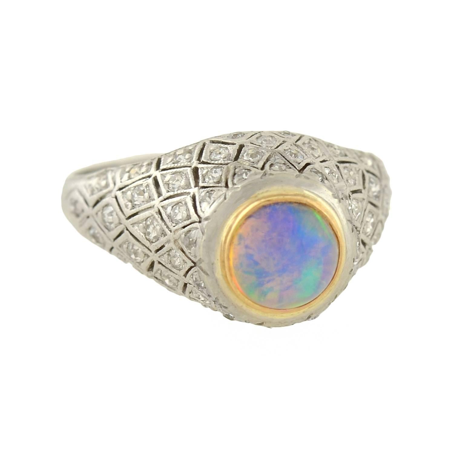 An absolutely stunning diamond and opal ring from the early Art Deco (ca1915) era! Made of platinum, this wonderful piece has a vibrant opal set at the center of its diamond encrusted mounting. The opal is closed back and bezel set in yellow gold