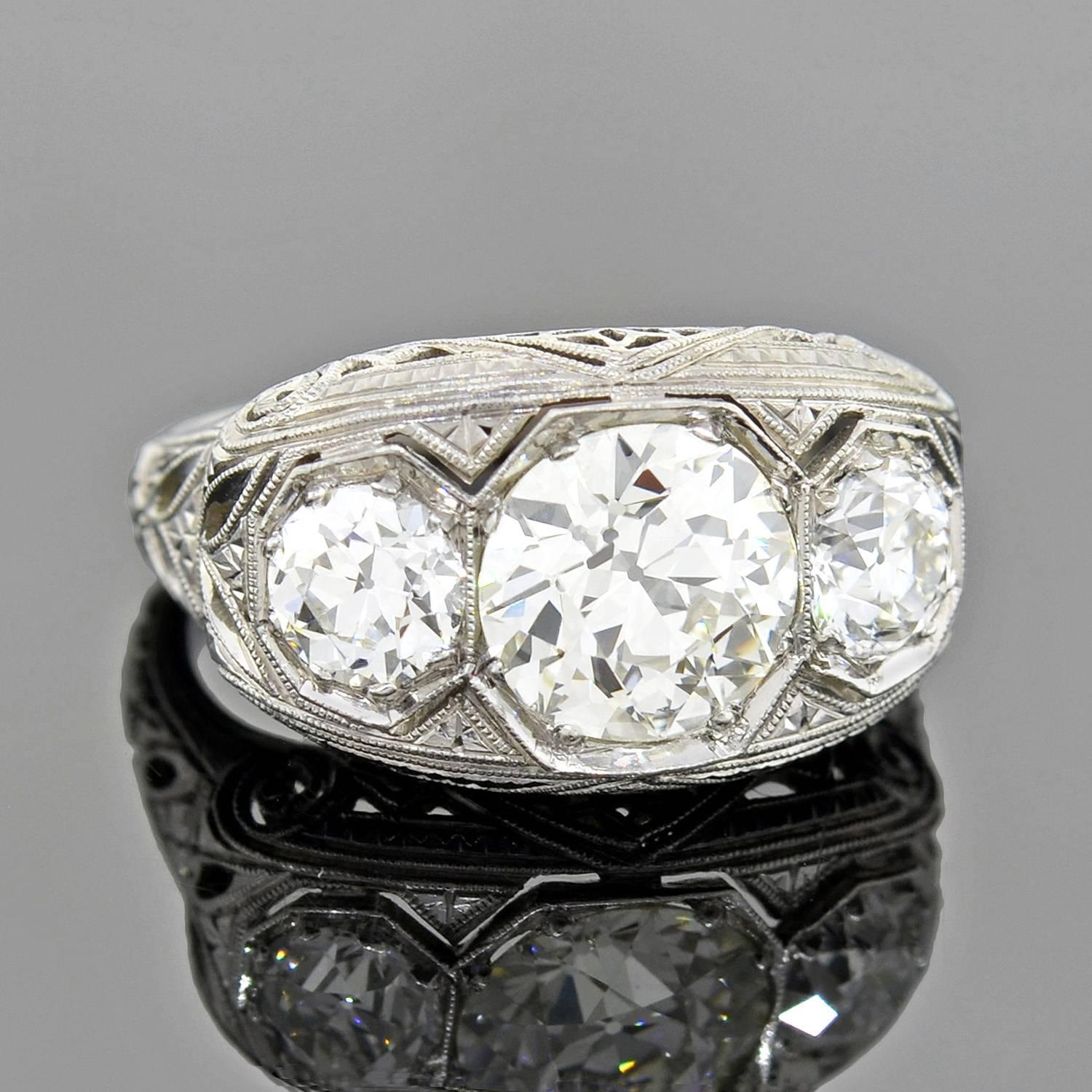 A lovely 3-stone diamond ring from the Art Deco (ca1920) era! This beautiful piece has three diamond stones that rests atop a delicate and ornate filigree mounting. The diamonds, which are old European Cut stones, have an approximate total weight of