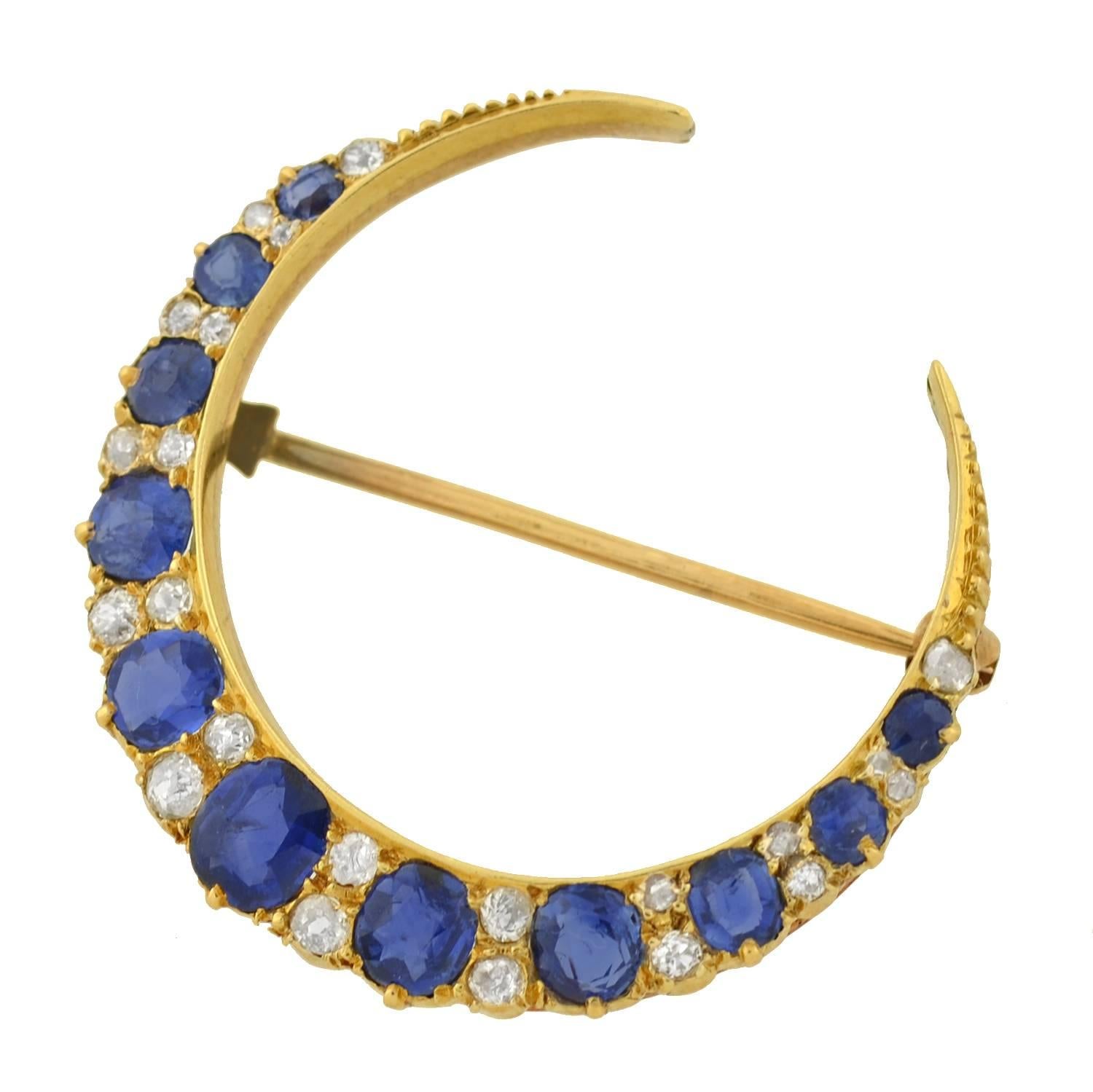A breathtaking sapphire and diamond crescent pin from the Victorian (ca1880) era! Made of 14kt yellow gold, this exquisite crescent moon piece adorns 11 vibrant sapphires which alternate with rows of 22 old Mine Cut diamonds. The stones graduate in