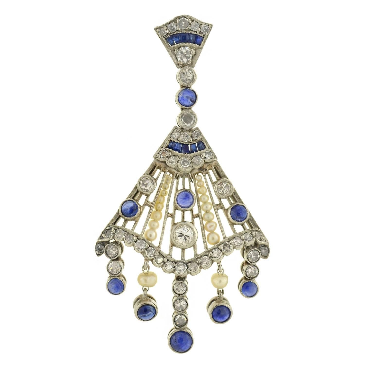 An exquisite pair of chandelier earrings! These incredible fan-shaped earrings are crafted in platinum and are quite substantial in size and appearance. A combination of sparkling diamonds, luscious cabochon sapphires, and natural seed pearls cover