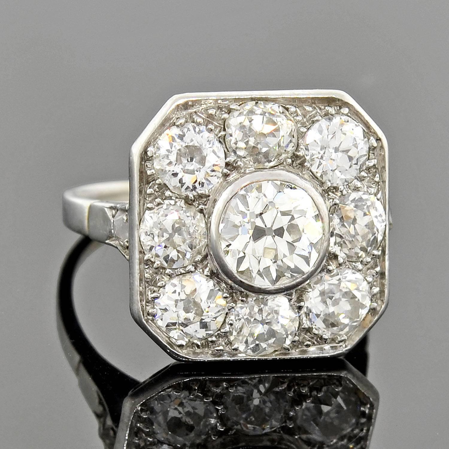 A striking diamond ring from the Edwardian (ca1910) era! This fabulous piece is made of platinum and adorns a large square-shaped face which which has clipped corners. The square centerpiece has a stunning design which is encrusted with 8 prong set