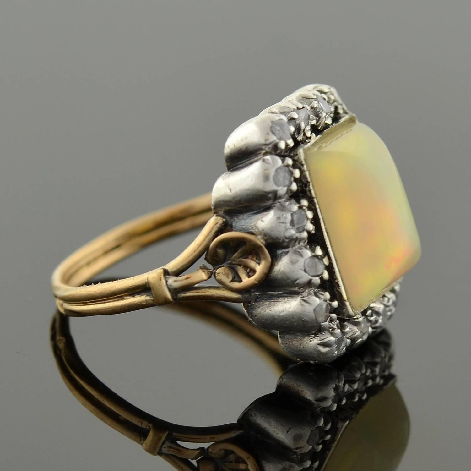 An enchanting opal ring from the Victorian (ca1880) era! This gorgeous ring is crafted in 18kt gold topped in sterling. An alluring white opal rests at the center, surrounded by a sparkling rose cut diamond border. The opal is simply mesmerizing,
