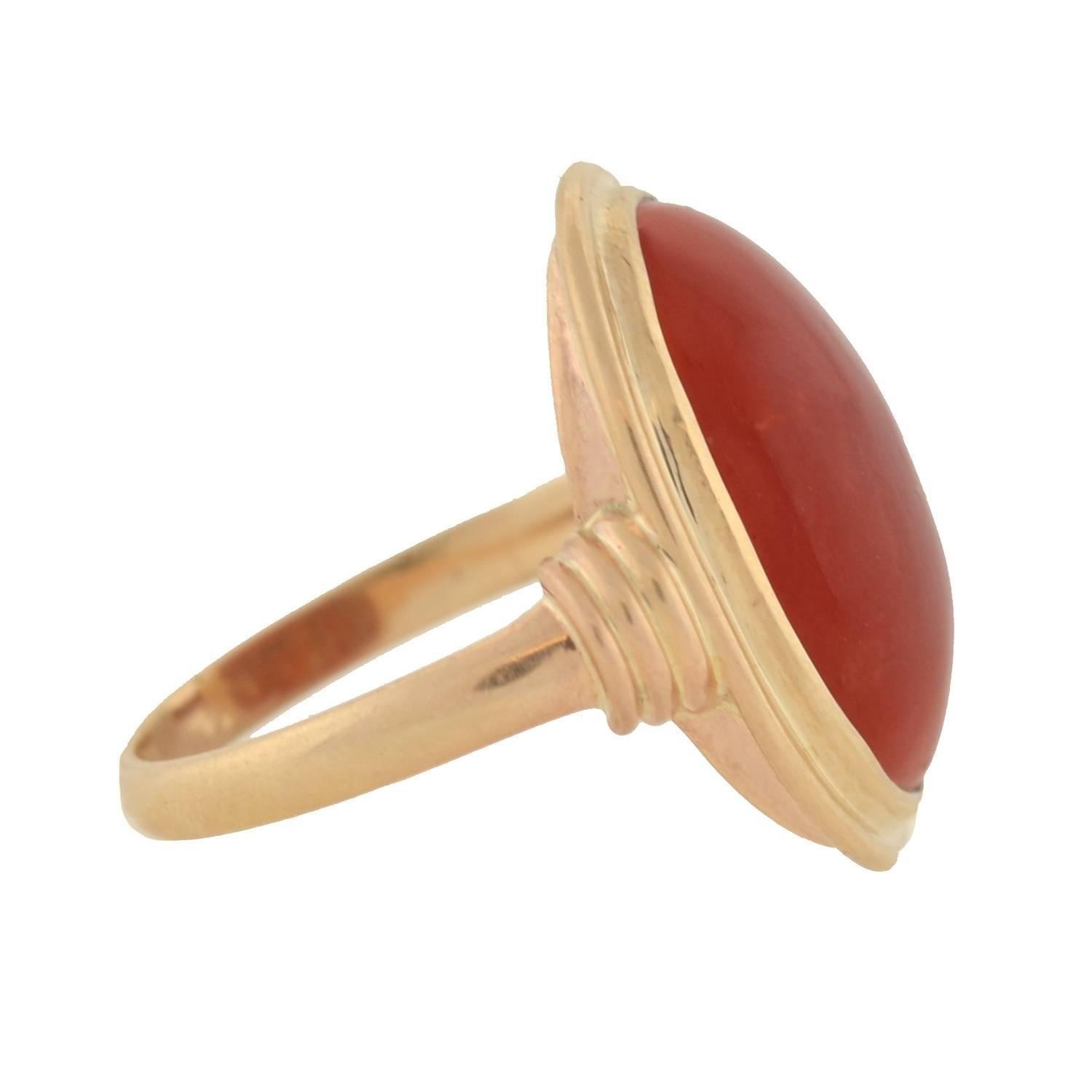 A simply beautiful natural coral ring from the early Retro (ca1930) era! Set in the center of this striking piece is a single large oxblood coral stone, which is bezel set in 14kt yellow gold. The coral rests within an oval shaped beveled frame