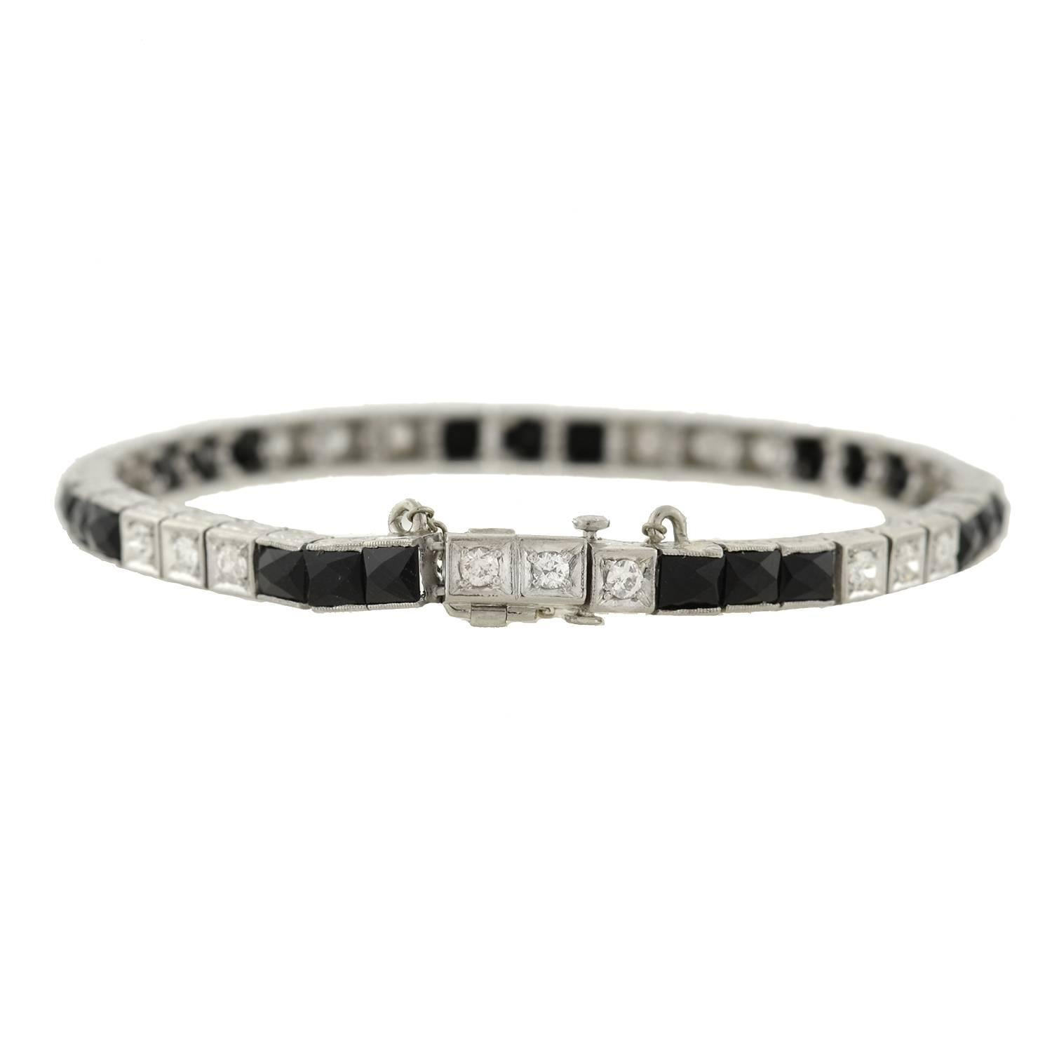 A gorgeous onyx and diamond line bracelet from the Art Deco era (ca1920)! This beautiful platinum bracelet features 21 French Cut onyx stone and 21 sparkling diamonds, which wrap around the entire length of the piece. The stones form an alternating