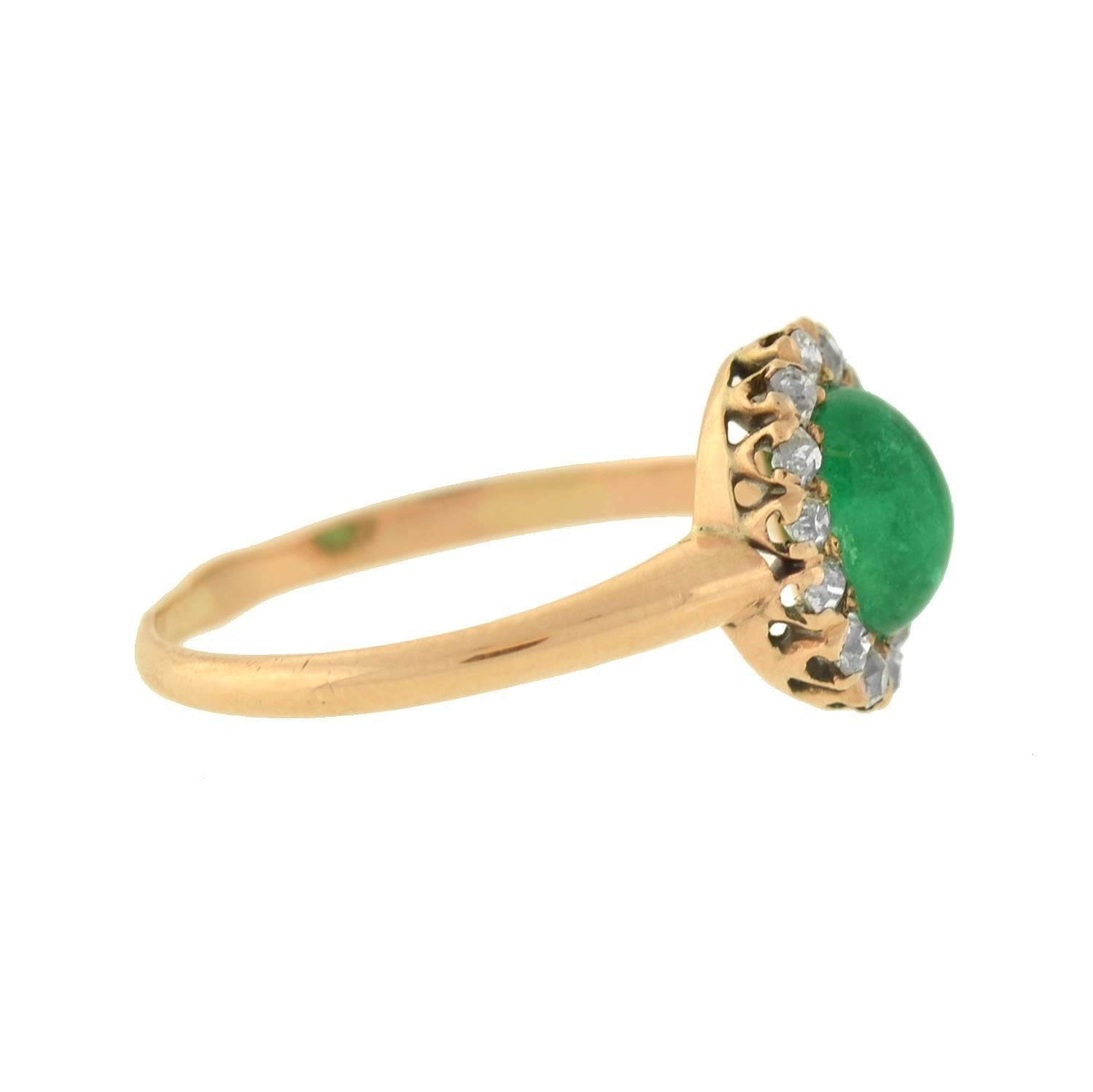 A beautiful emerald and diamond ring from the early (ca1920) Art Deco era! This ring is of Russian origin, and has a petite and feminine design crafted in 14kt gold. At the center is a luscious emerald cabochon, which is surrounded by a border of