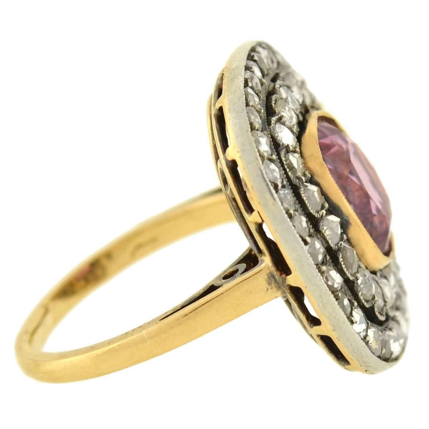 A magnificent gemstone ring statement ring . Crafted in 18kt gold and topped in sterling silver, the ring boasts a dazzling centerpiece with a diamond-encrusted surface. Resting at the center is a natural no-heat pink spinel, which is bezel set and