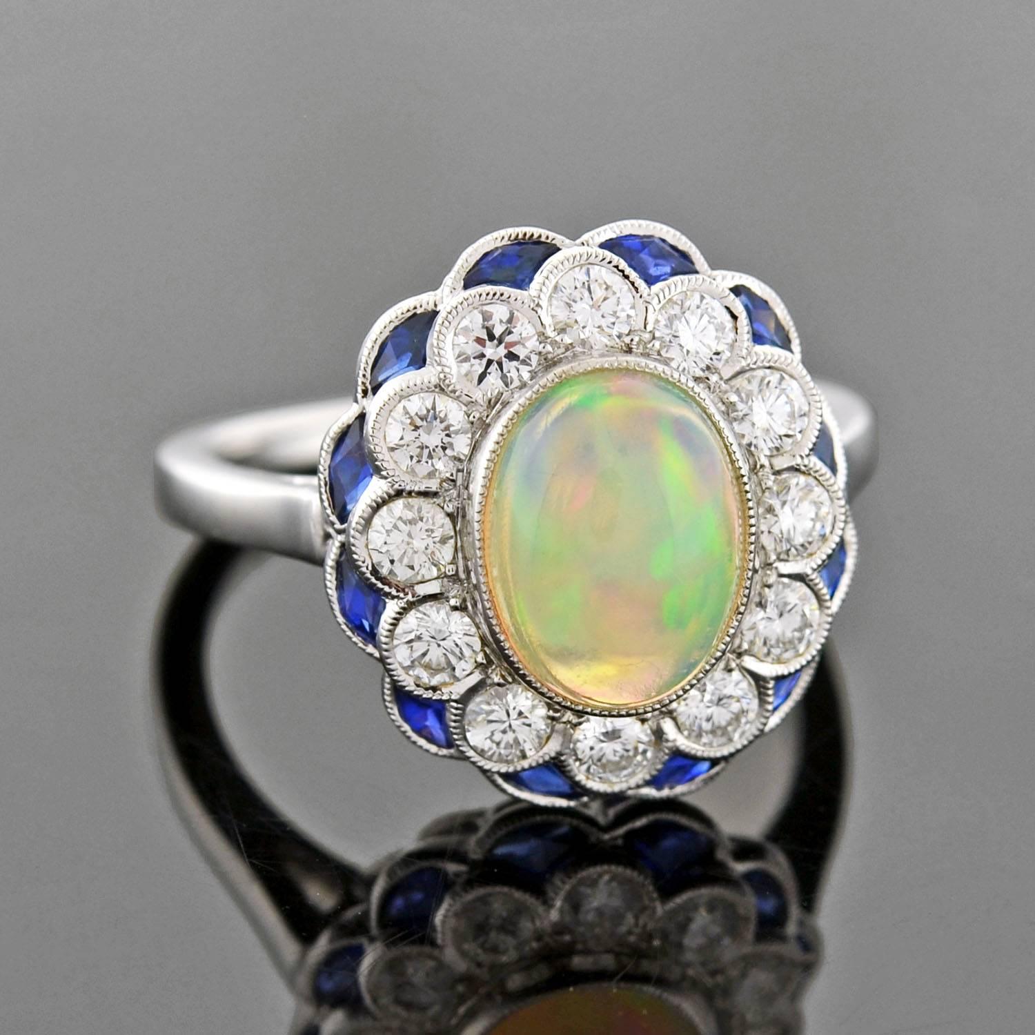 A simply exquisite estate opal ring! This fabulous piece is made of 18kt white gold and has a single oval-shaped cabochon opal stone set in its center. The stone, which is large in size, is bezel set and has magnificent color with hues of green,