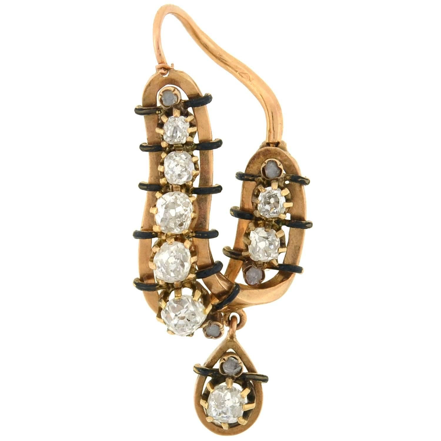 A magnificent pair of earrings from the Victorian (ca1880) era! These unusual earrings are French in origin, and boast an artistic asymmetrical design. Crafted in 18kt gold, the curvy framework is topped with sparkling diamonds and rich black enamel