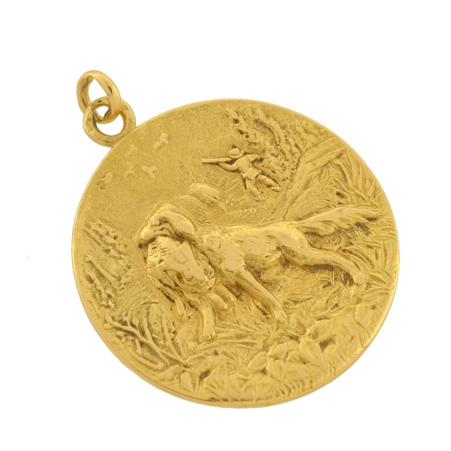 This lovely gold pendant from the Edwardian era (ca1910) is a signed piece by Cartier! Crafted in vibrant 18kt yellow gold, the pendant displays a hunting scene. The raised image is intricately detailed, depicting the grassy countryside with trees