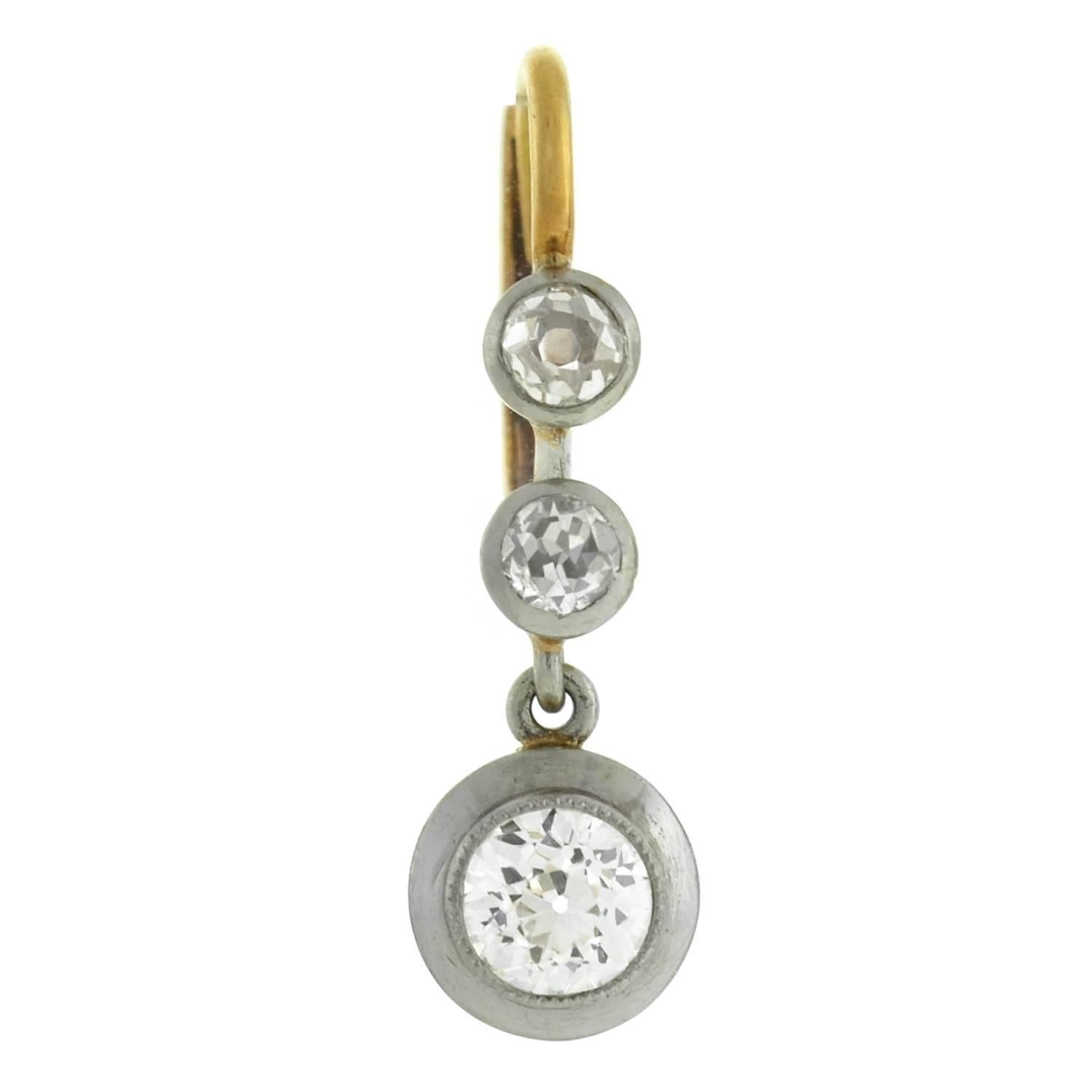 An exquisite pair of elegant diamond drop earrings! Crafted in 18kt gold and platinum, these Edwardian era earrings (ca1910) have a stunning old Mine Cut diamond encrusted design. The surface of each earring is lined with a three bezel set stones,