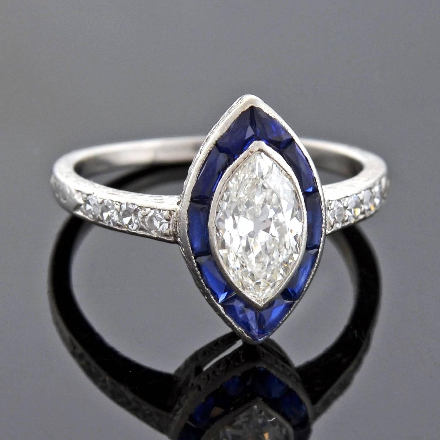 A gorgeous diamond and sapphire ring from the Art Deco (ca1920) era! Made of platinum, the ring frames a sparkling marquise diamond at the center of a sapphire border. The central diamond weighs 1.00ct, and has K color and VS2 clarity. Lining the