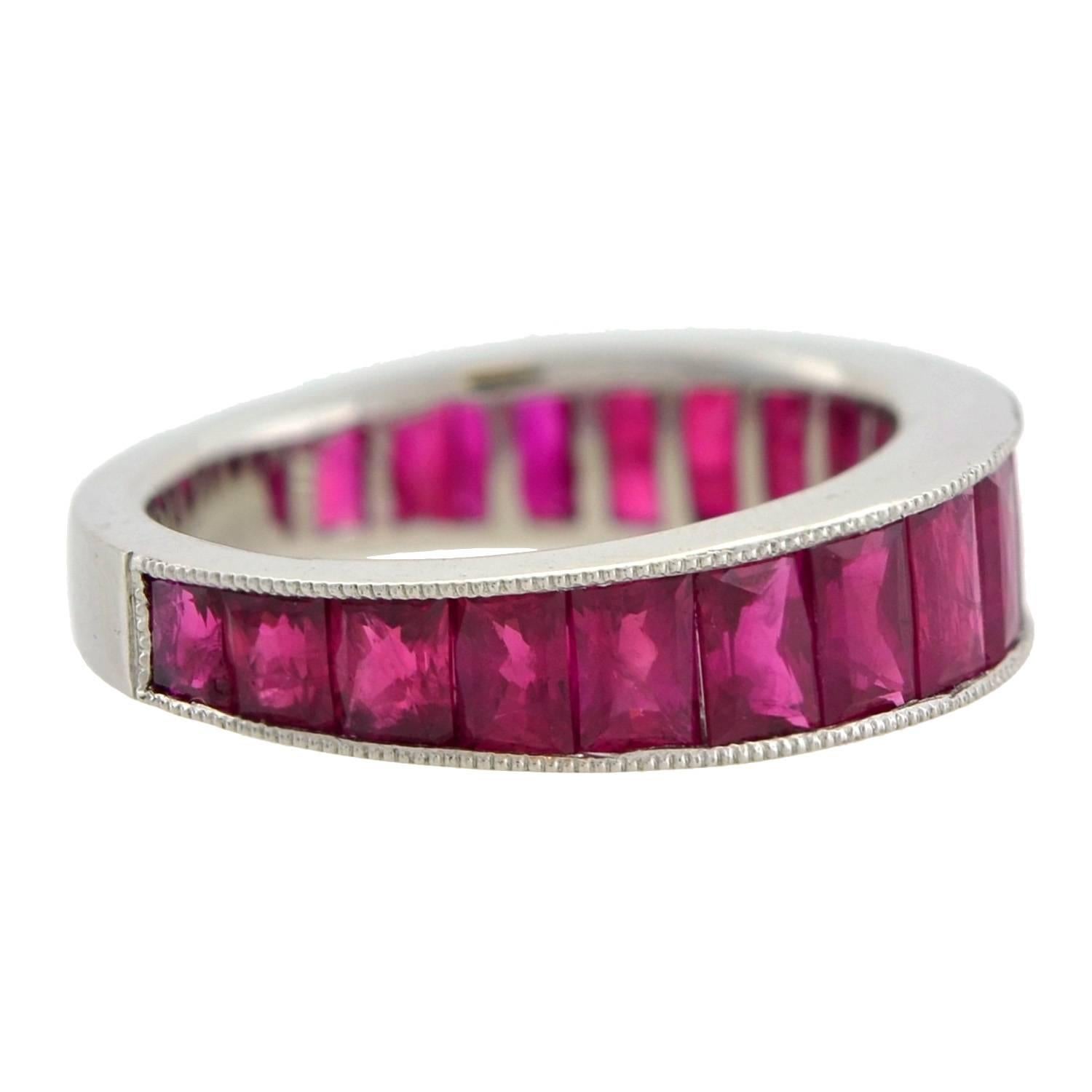 This fantastic ruby eternity band has a stunningly substantial look and feel! Made of platinum, the wide band holds a seamless row of 19 luscious Burmese rubies in a smooth channel setting. The calibrated rubies are French cut stones and graduate in