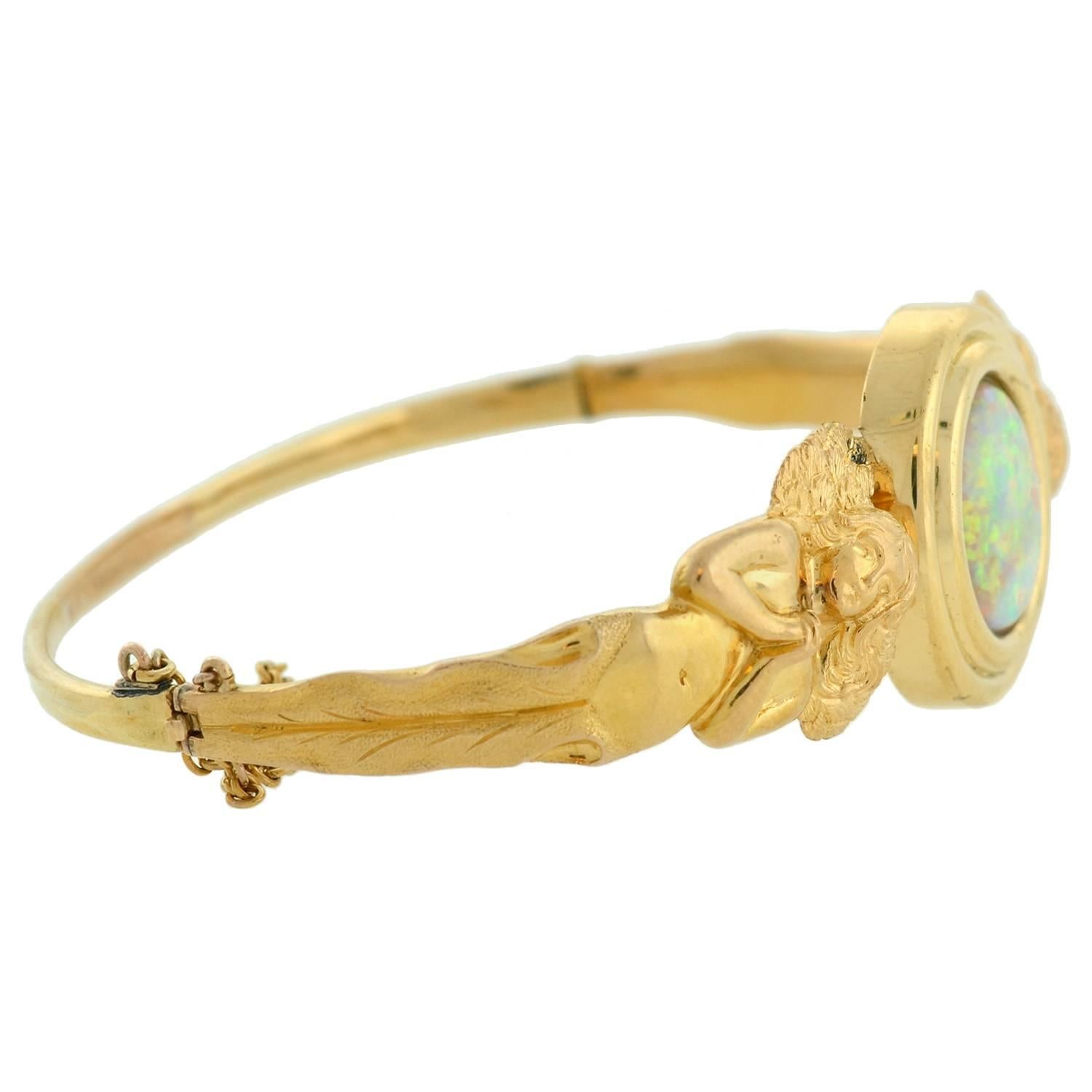 A beautiful and unusual opal bracelet from the 1900s! Made of 18kt yellow gold, this gorgeous piece carries a wonderful and romantic angelic design. Set in the belly front of the bracelet is a vivid opal stone which is oval shaped and substantial in