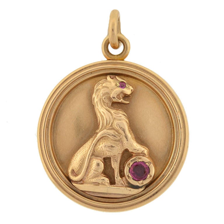 An exquisite and collectable double sided locket from the Victorian (ca1880) era. This stunning piece is made of 14kt rosy yellow gold and round in shape. On the front is the raised body of a lion which has a single ruby set in the eye and a larger