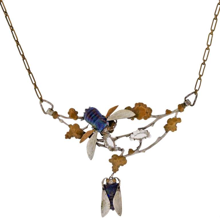 An artistic and very unusual French necklace from the Art Nouveau (ca1900) era! This unique piece hangs from a brass link chain and features an elaborate silver and art glass centerpiece below. The centerpiece is quite large in size, and depicts a
