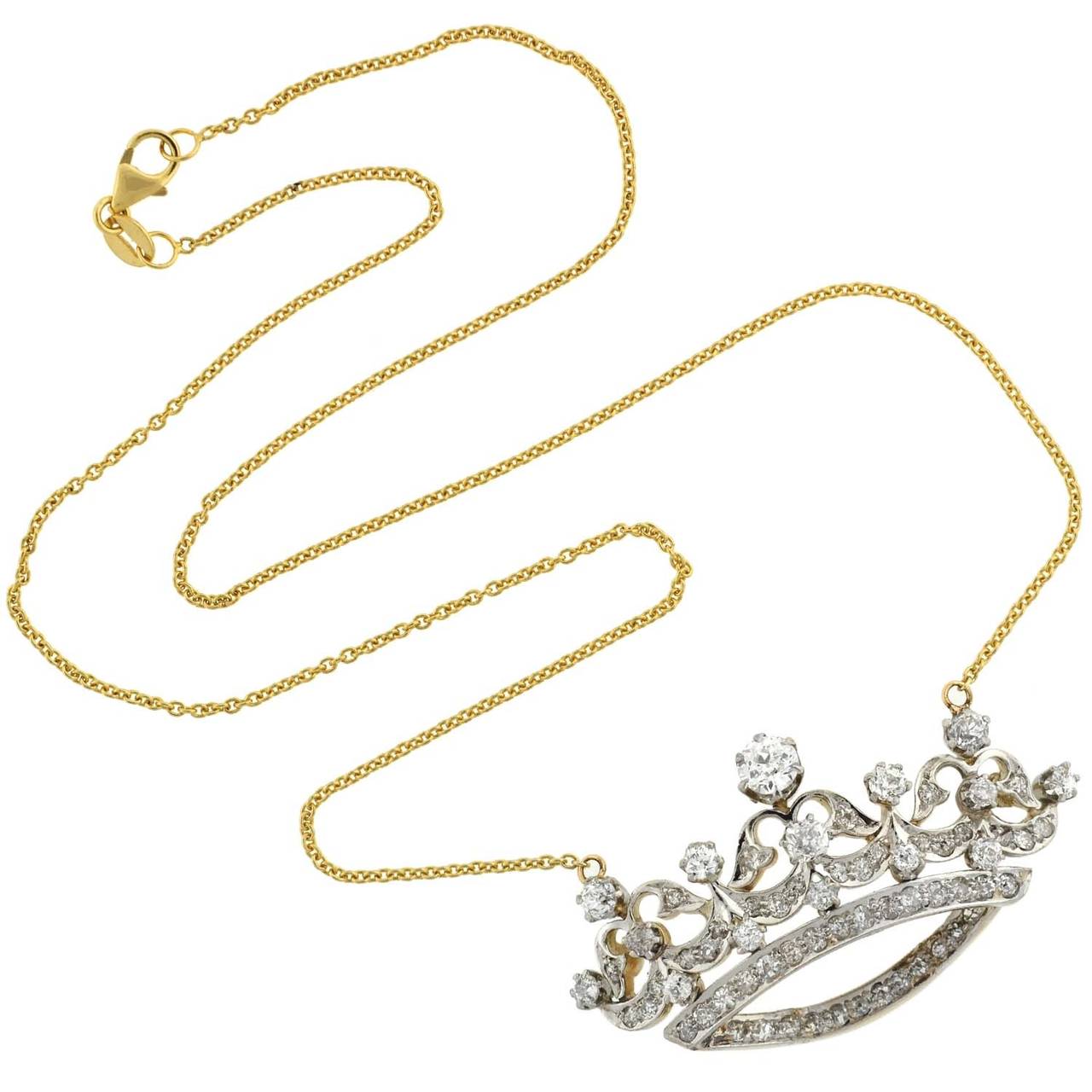 A spectacular diamond crown necklace from the Edwardian (ca1910) era! This exquisite piece is comprised of a crown pendant made of platinum-topped 14kt gold, which hangs from a vibrant gold chain. The crown has flowing, feminine design, and features