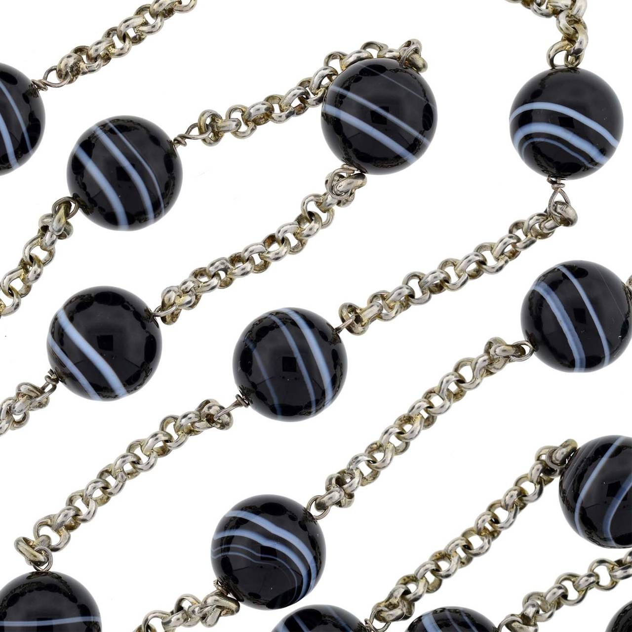 A bold Estate sterling and agate chain necklace! Extremely long in length, this fabulous piece is comprised of sections of sterling silver chain that alternate with large banded agate beads. The chain has a simple round link and attaches to each