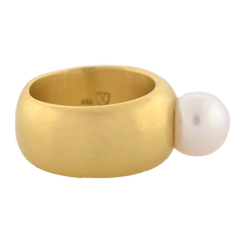 A fabulous Estate gold pearl ring! This beautiful piece is made of vibrant 18kt yellow gold which has a wonderful, matte finish. At the center of the wide band ring is a single lustrous pearl, sitting raised above the surface. The design is simple