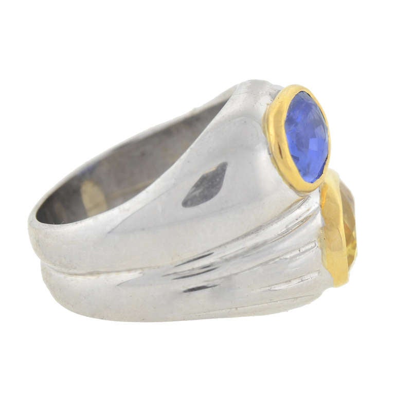 This striking double sapphire Estate ring is a fabulous signed piece by Bulgari! Made of 18kt white gold, this unique piece has a stunning stacked ring design. Each band holds a large bezel set sapphire, one blue and one yellow, each resting