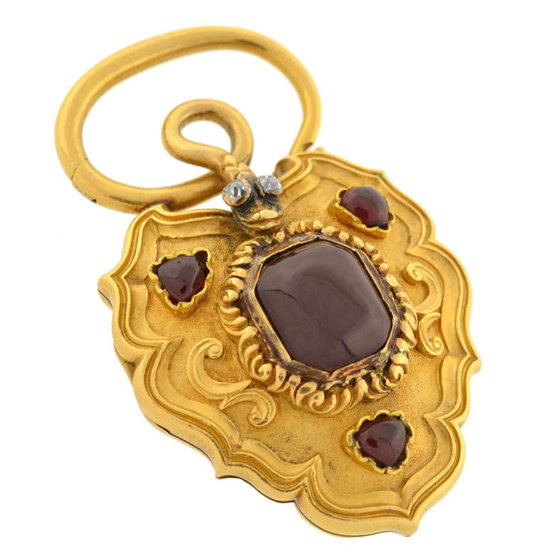 An exquisite gold padlock locket from the Victorian (ca1880) era! This beautiful piece is made of vibrant 18kt yellow gold and forms the shape of a large padlock with an ornate design. Resting on the front surface are three garnet cabochon stones,
