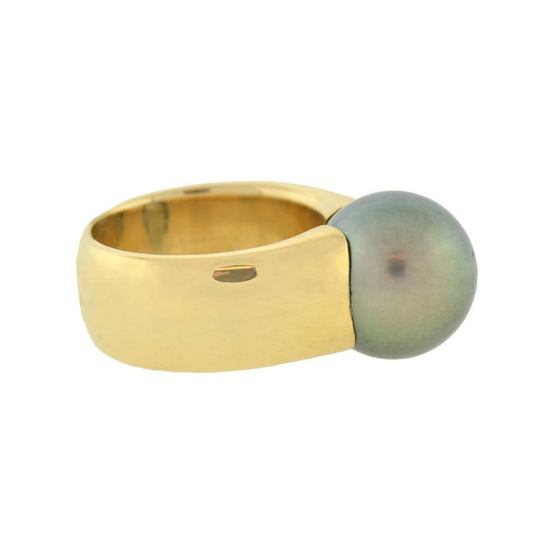 An absolutely fabulous Estate gold and pearl ring! This beautiful piece is made of vibrant 18kt yellow gold, which forms a thick, wide band. The two ends of the band meet in the middle at a single lustrous Tahitian pearl, which rests in the center