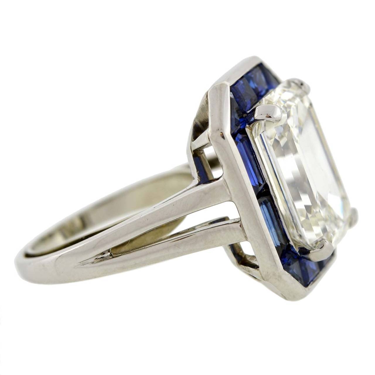 This Oscar Heyman estate ring from the 1980s is a breathtaking beauty of magnificent proportions! A spectacular 8.38ct Emerald Cut diamond is prong set within the platinum mounting. Surrounding the diamond is a border of vivid sapphires, which