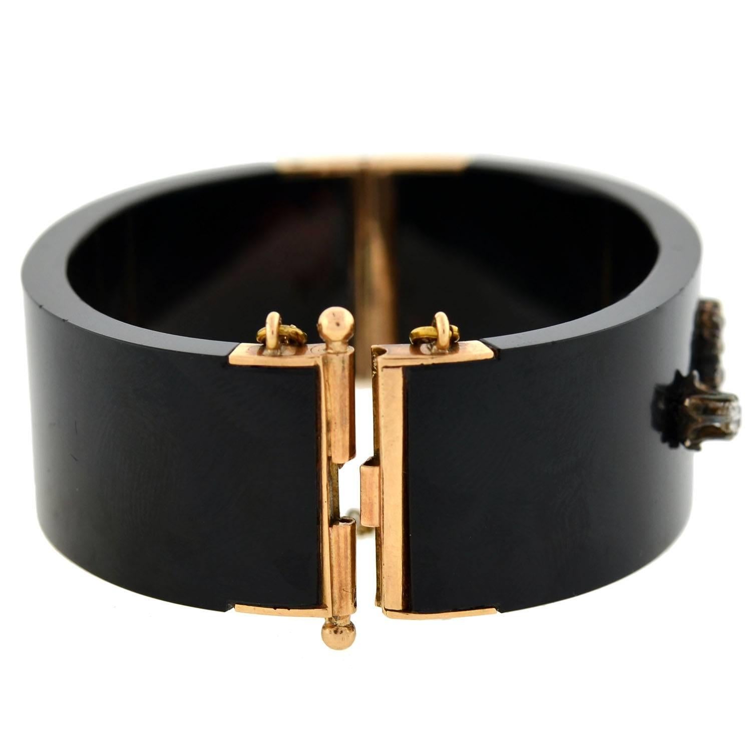 A gorgeous bangle bracelet from the Victorian (ca1880) era! This fantastic piece is fitted with beautiful 14kt rose gold findings and carved from rich black onyx stone, which is smoothly polished for a glossy finish. Decorating the face of the