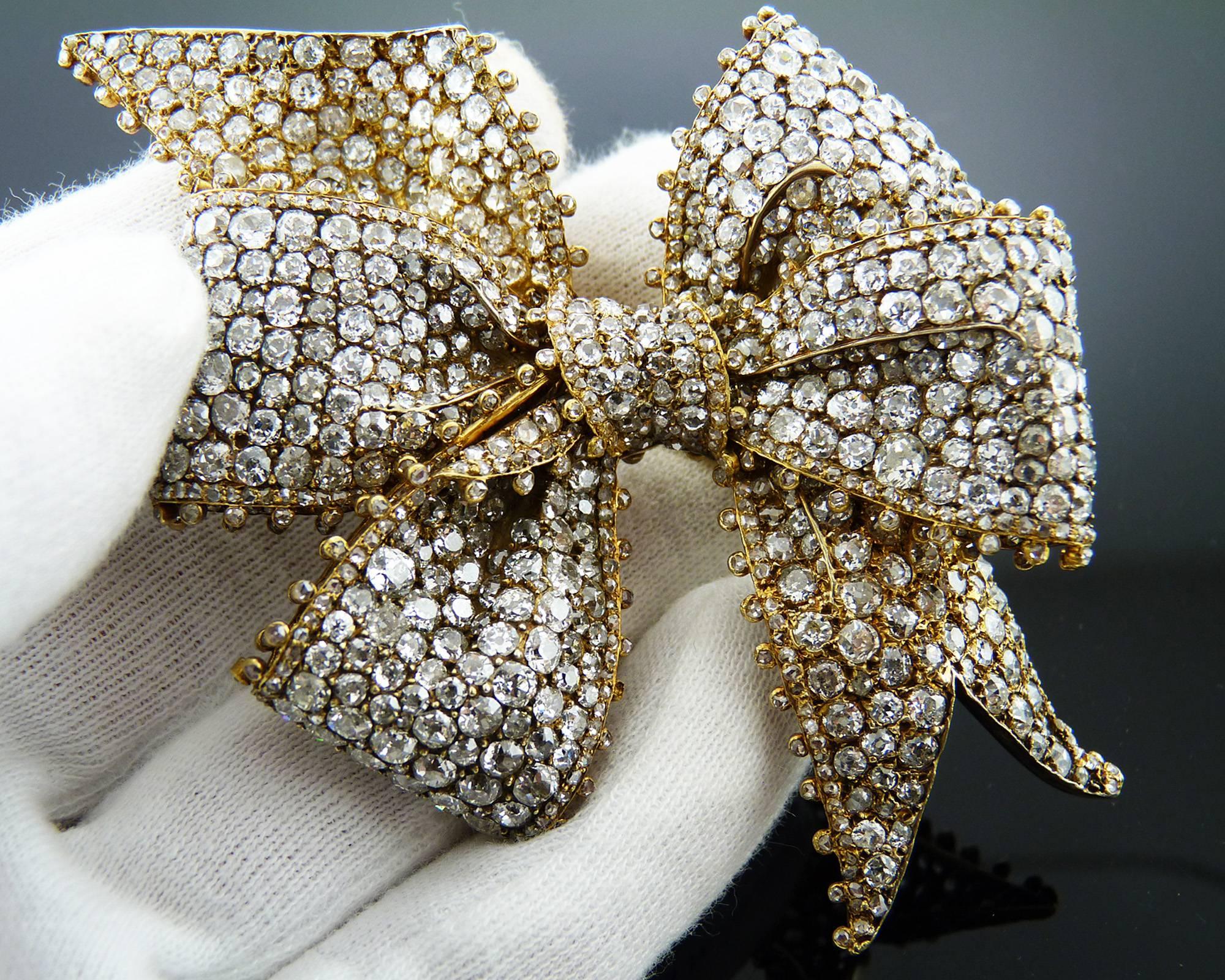 An elegant antique diamond bow brooch with the tied ribbon set with old mine, old European and rose-cut diamonds, to the diamond collet trim, mounted in 18K yellow gold. 
Diamonds are very bright and lively, graded E-F color, and VS clarity.
Total