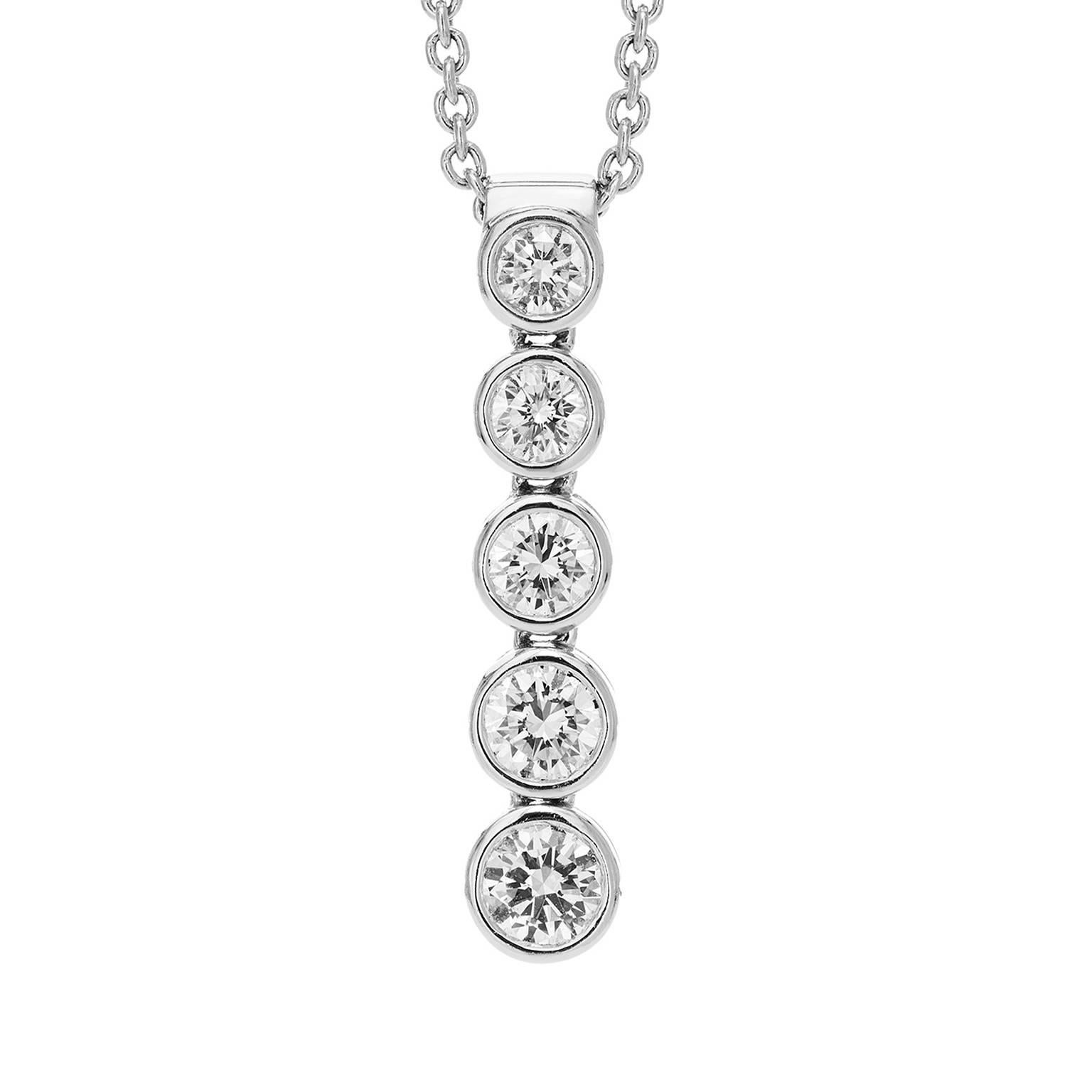 A single row of five diamonds in graduating size cascade downwards in a flexible setting, total carat weight 0.94ct. Colour grade E. Clarity grade VS1-VS2.

Set in 18K white gold. Adjustable chain can be worn at 17" or 16".

Length of