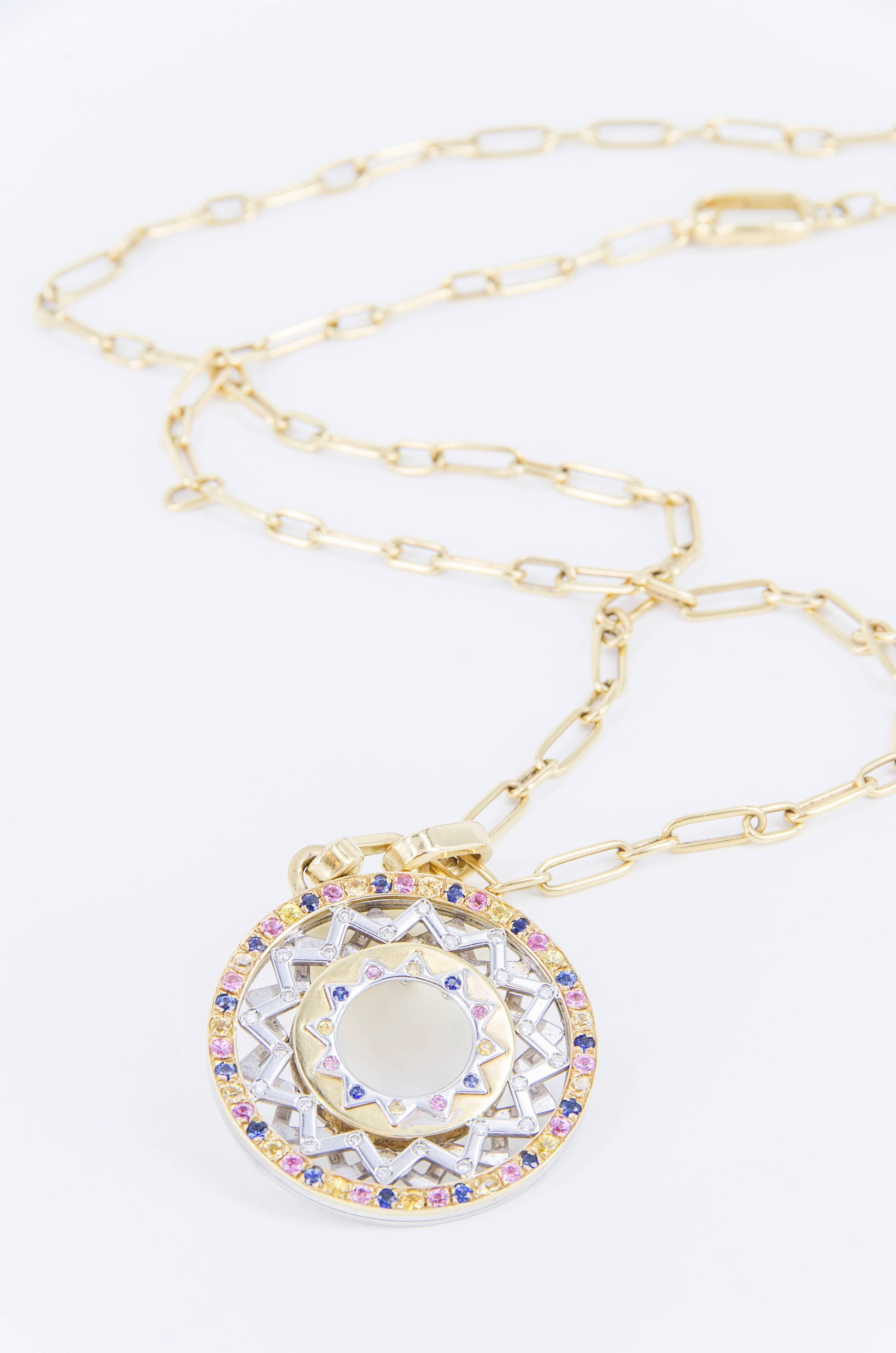 Pendant designed by Anna Gili, edited by Nicolis Cola in 2001. White and yellow gold, 24 white brilliants (0,24 ct.), 57 yellow, pink and blue sapphires (1,86 ct.). 