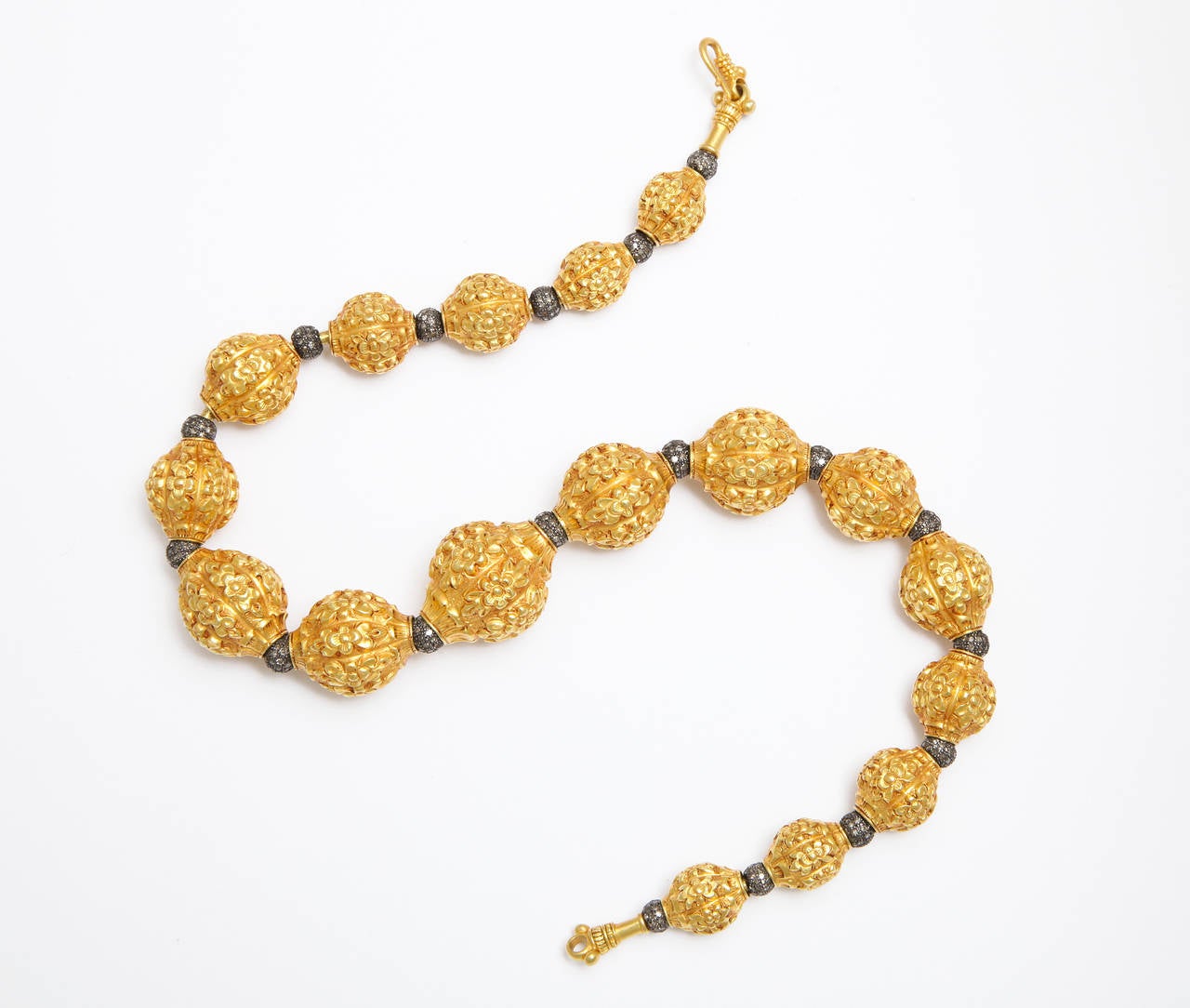 A necklace composed of 17 graduated 22kt yellow gold repousse floral beads and 18 rhodium plated sterling silver and diamond beads. The beads run through an 18kt yellow gold rope necklace. There are approximately 8.54cts of diamonds.