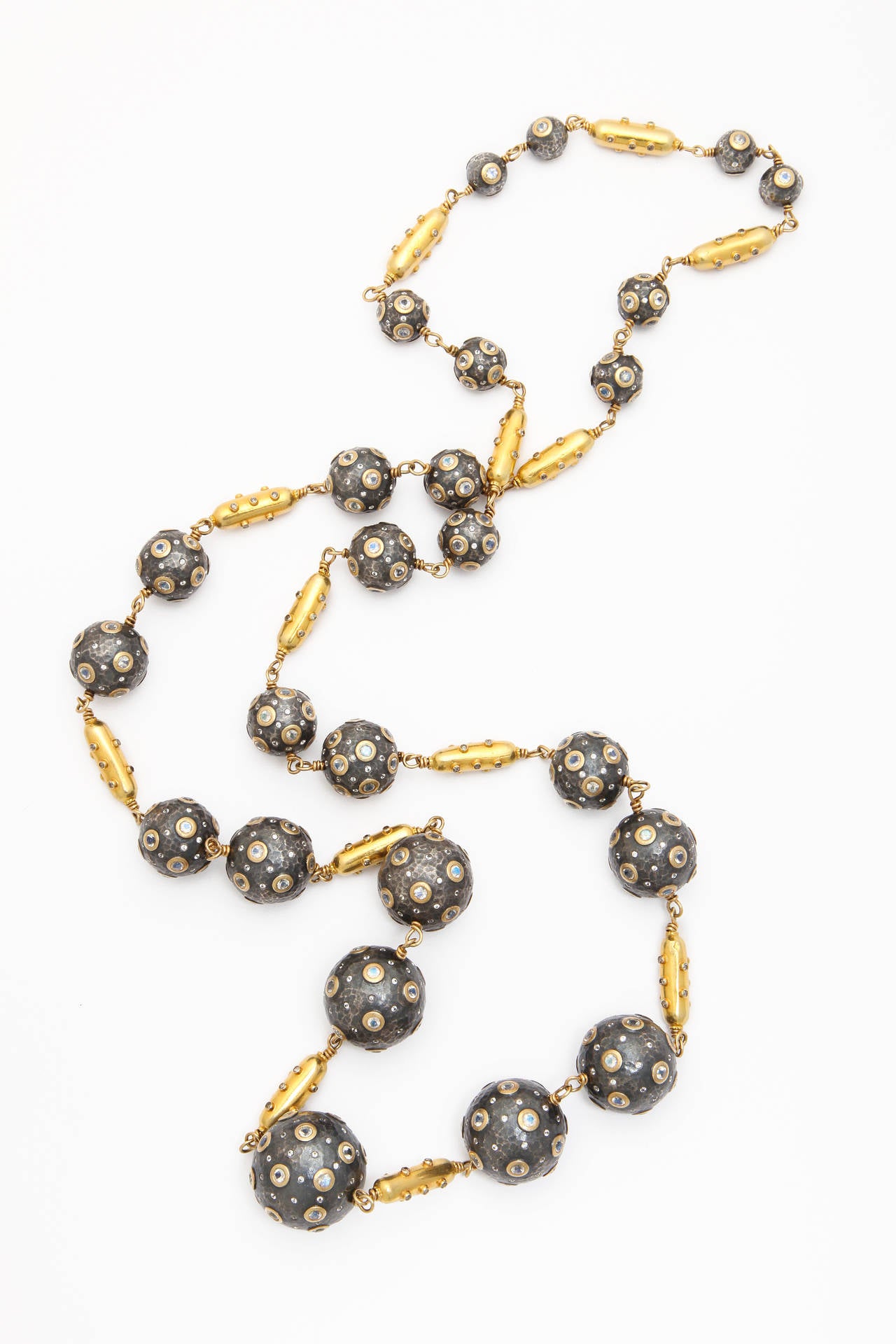 A necklace composed of 18kt yellow gold and diamond capsule beads and rhodium plated sterling silver beads set with gold bezel set moonstones and white sapphires. The beads are linked together by a handmade 18kt yellow gold chain.There are 11.60cts