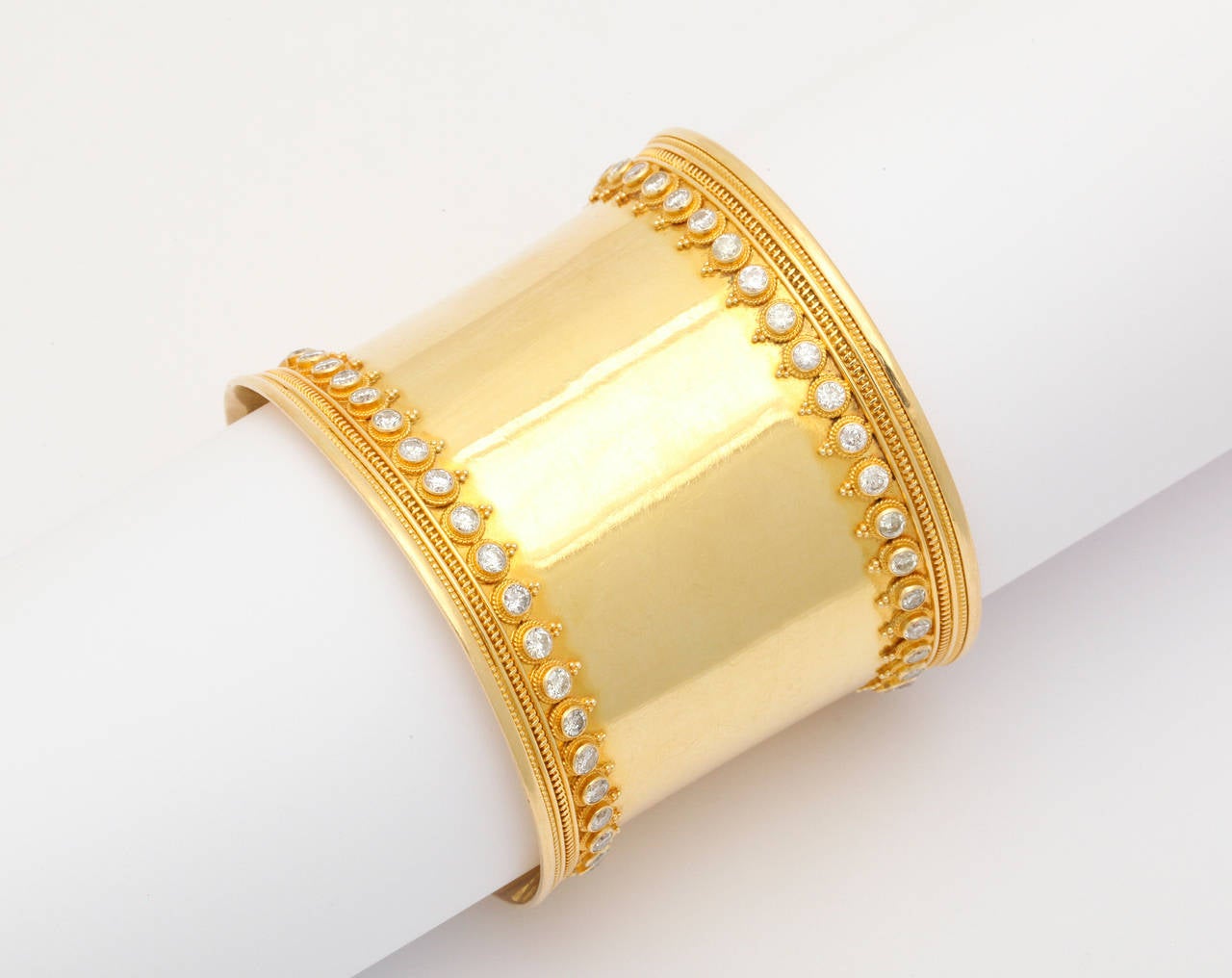 An 18kt yellow gold and diamond cuff. The gold cuff has a ribbed frame and is set with round brilliant cut diamonds. The diamonds are set in gold granulated bead flowers. There are approximately 6.25cts of diamonds.