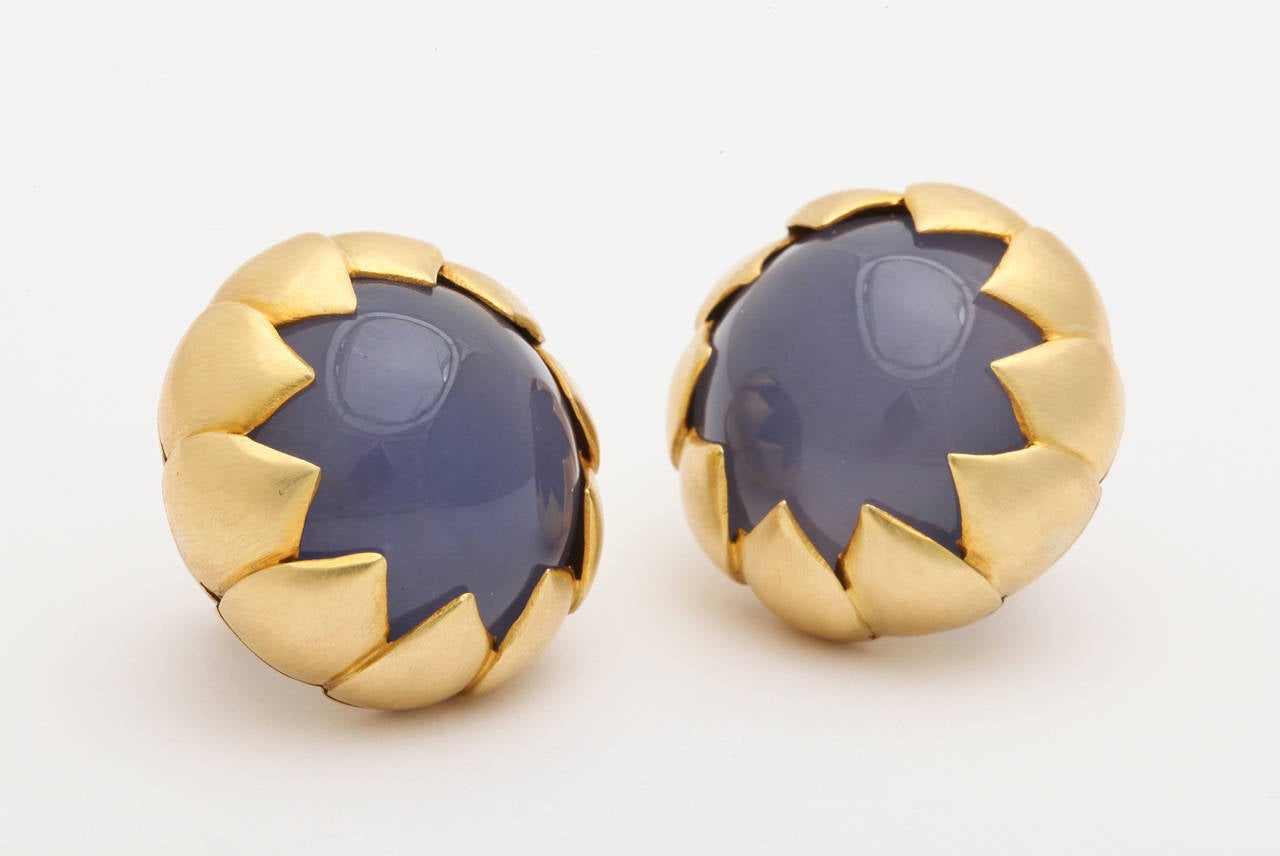 A pair of earrings composed of carved cabochon chalcedony stones that are set in18kt yellow gold petal jackets.